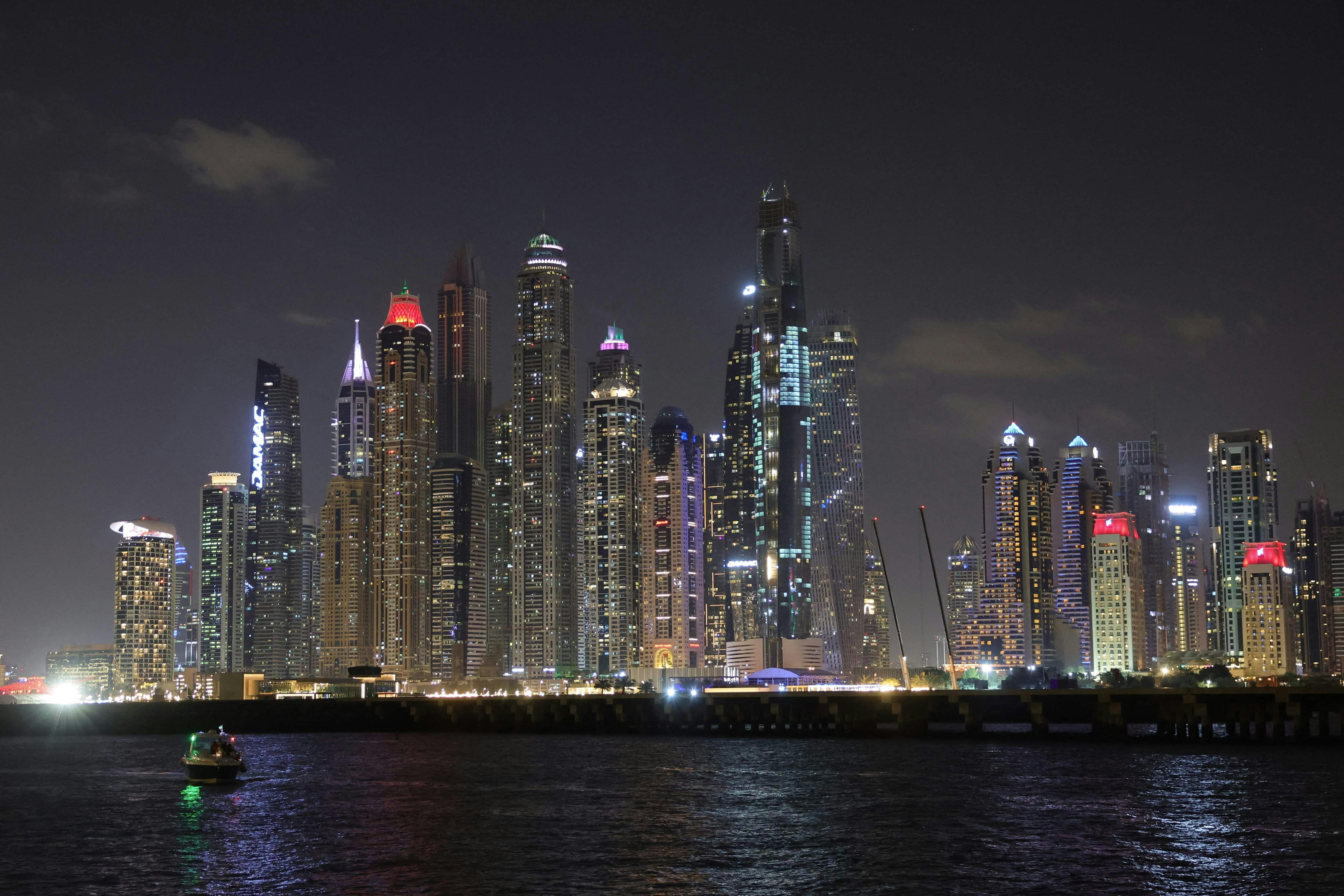 TOPSHOT - A boat sails on a night ride at the Dubai marina with a view of the Gulf emirate's skyline on December 15, 2023. (Photo by Giuseppe CACACE / AFP)