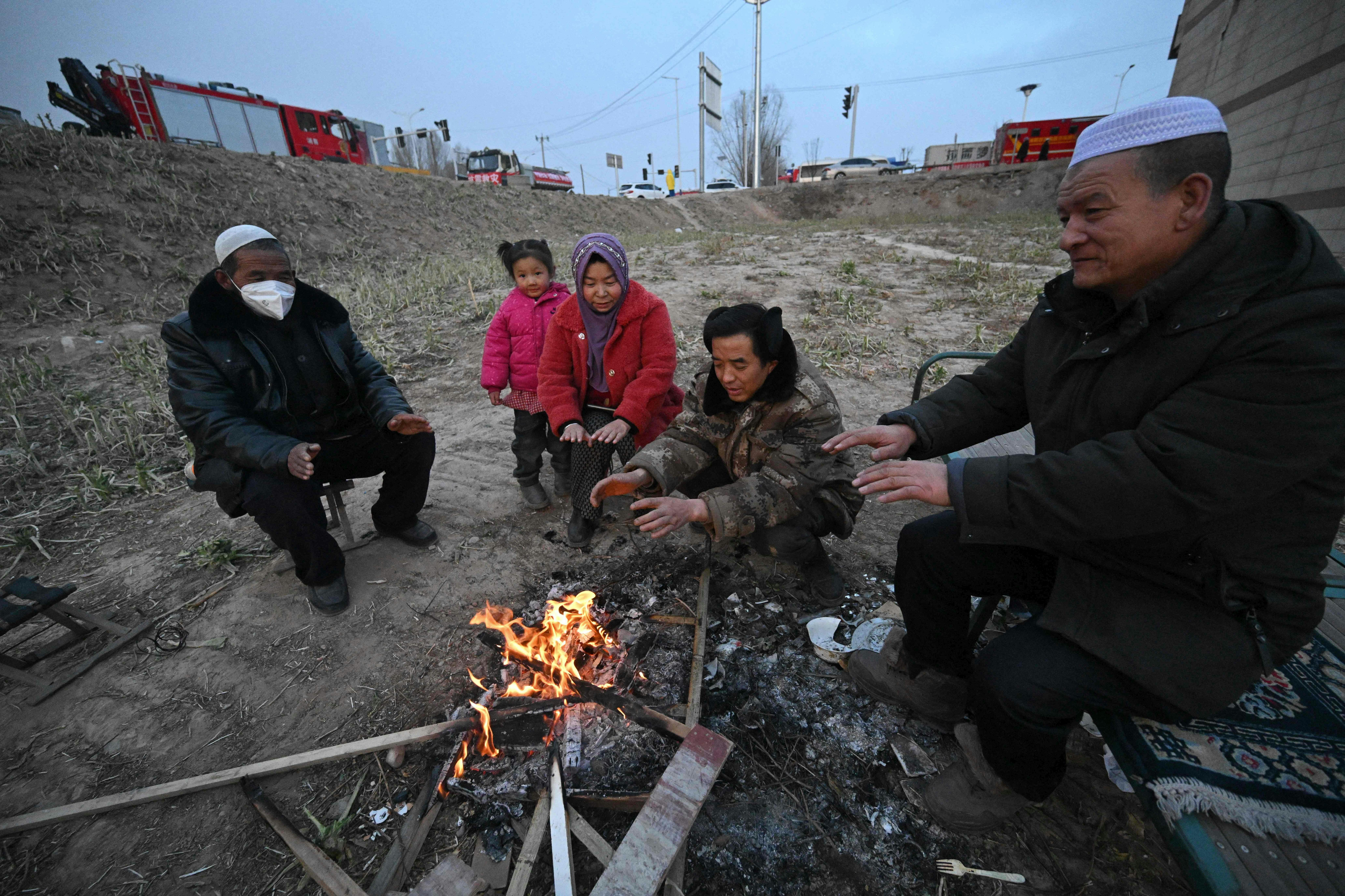 TOPSHOT - People gather next to a fire after an earthquake in Dahejia, Jishishan County in northwest China's Gansu province on December 19, 2023. (Photo by Pedro Pardo / AFP)