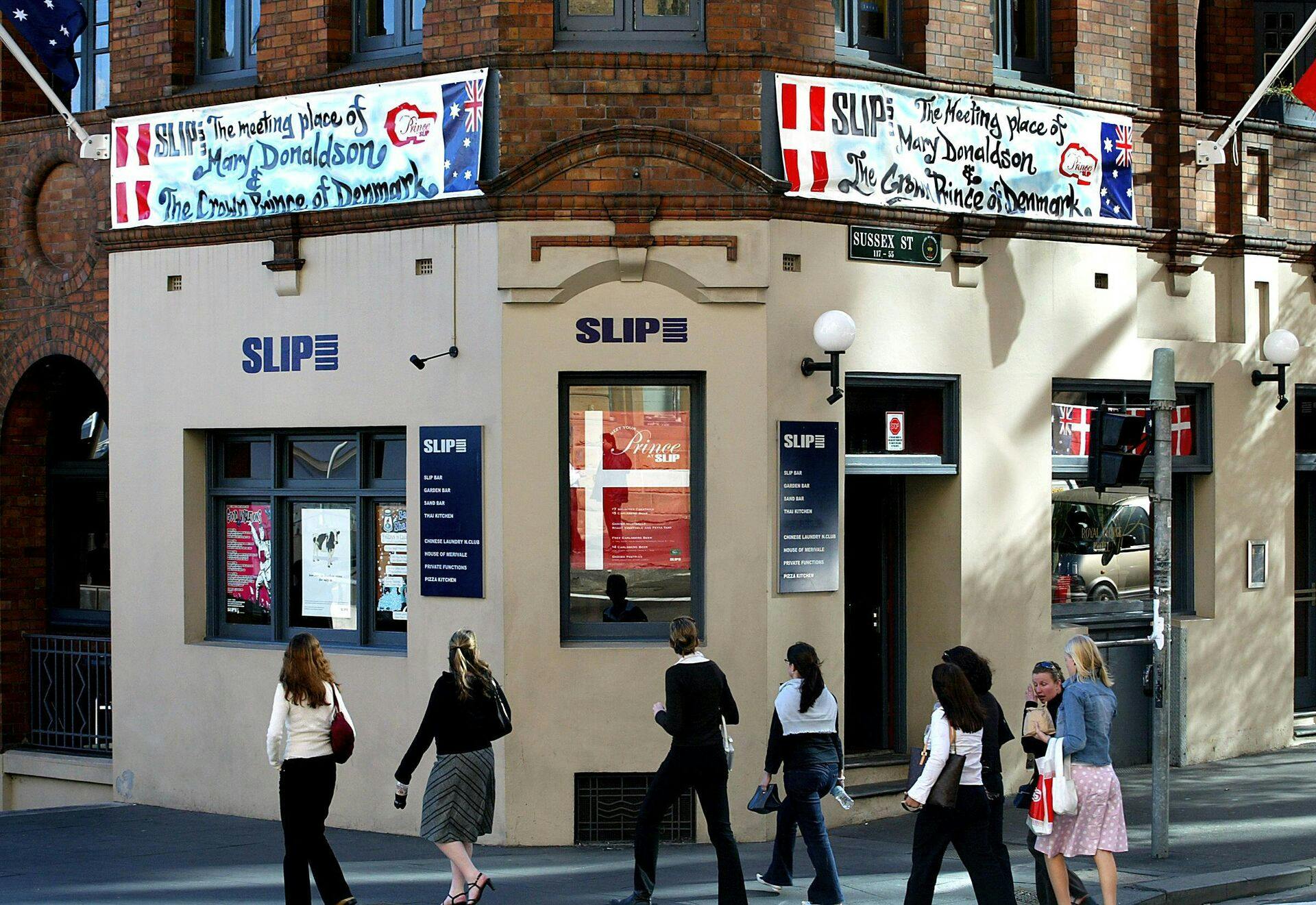 Pedestrians walk past the Slip Inn in Sydney, 13 May 2004, where signs are displayed (top) which say "The meeting place of Mary Donaldson and the Crown Prince of Denmark". Tasmanian lawyer Mary Donaldson met Danish Crown Prince Frederick at the Slip Inn in central Sydney during the 2000 Olympic Games, with the pair now set marry in Copenhagen 14 May. AFP PHOTO/Greg WOOD