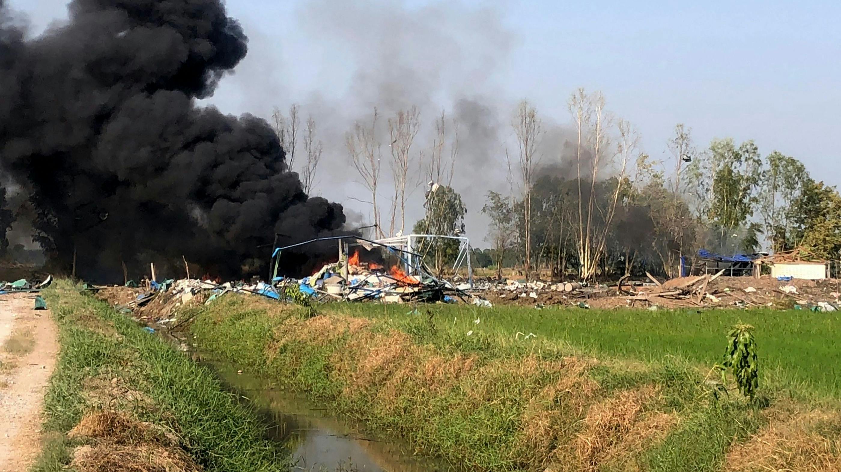 Røg stiger op fra området i Suphan Buri i det centrale Thailand, hvor en tragisk fyrværkeriulykke på en fabrik har krævet adskillige menneskeliv