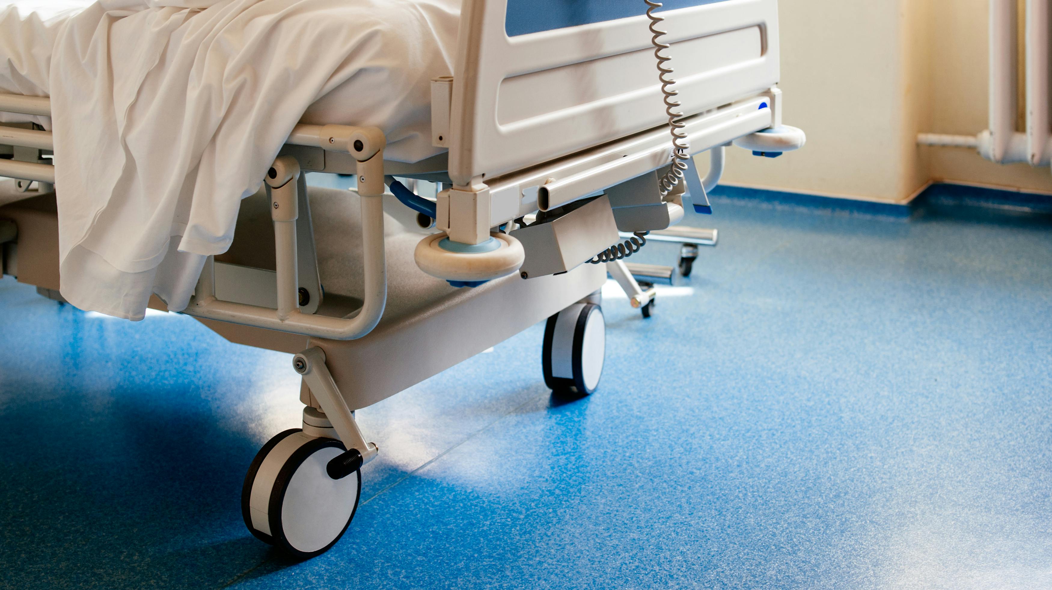 Empty modern hospital bed in a sunny room with a clean blue floor