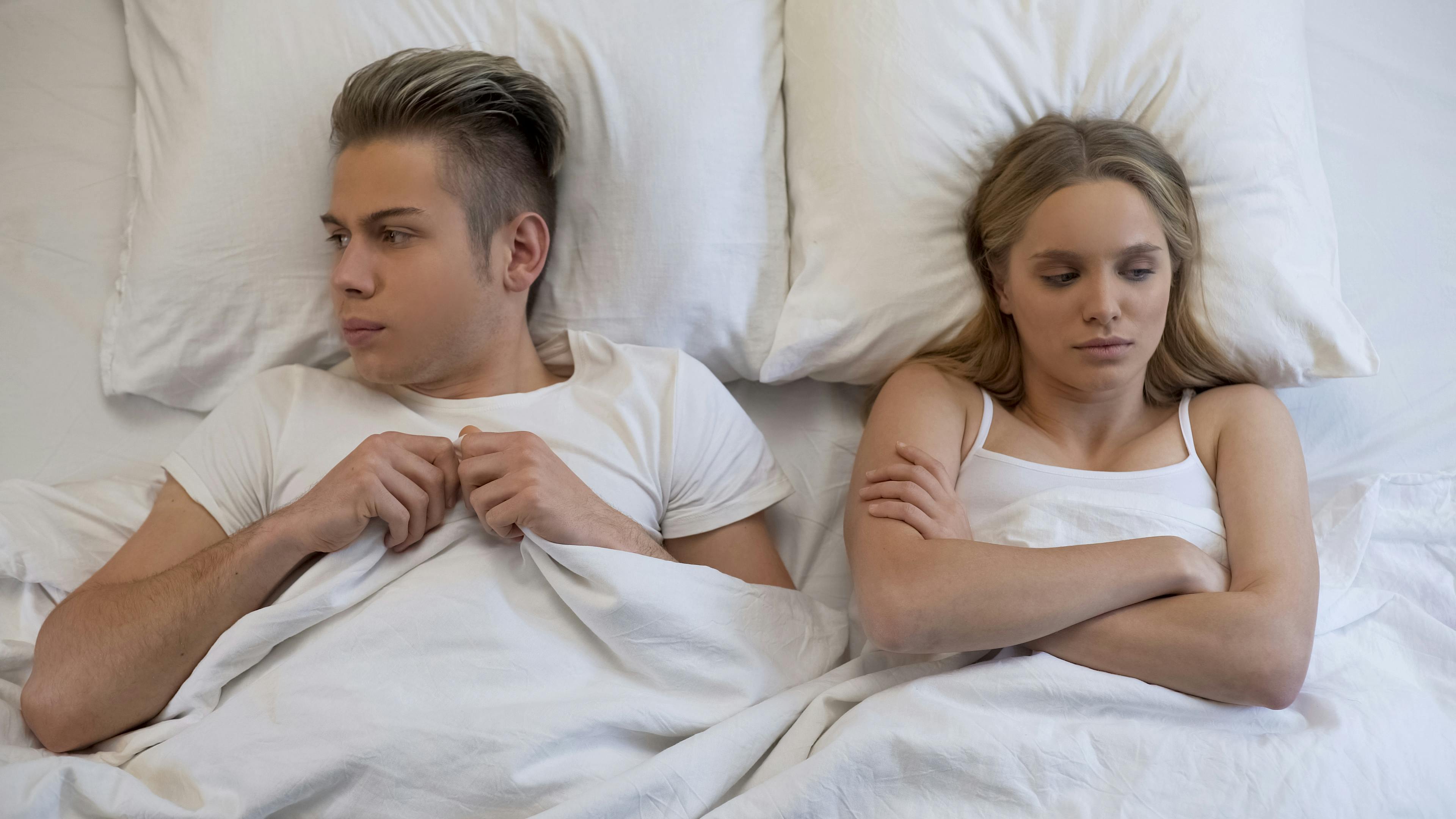 Young wife looking dissatisfied with first sex experience, embarrassed boyfriend