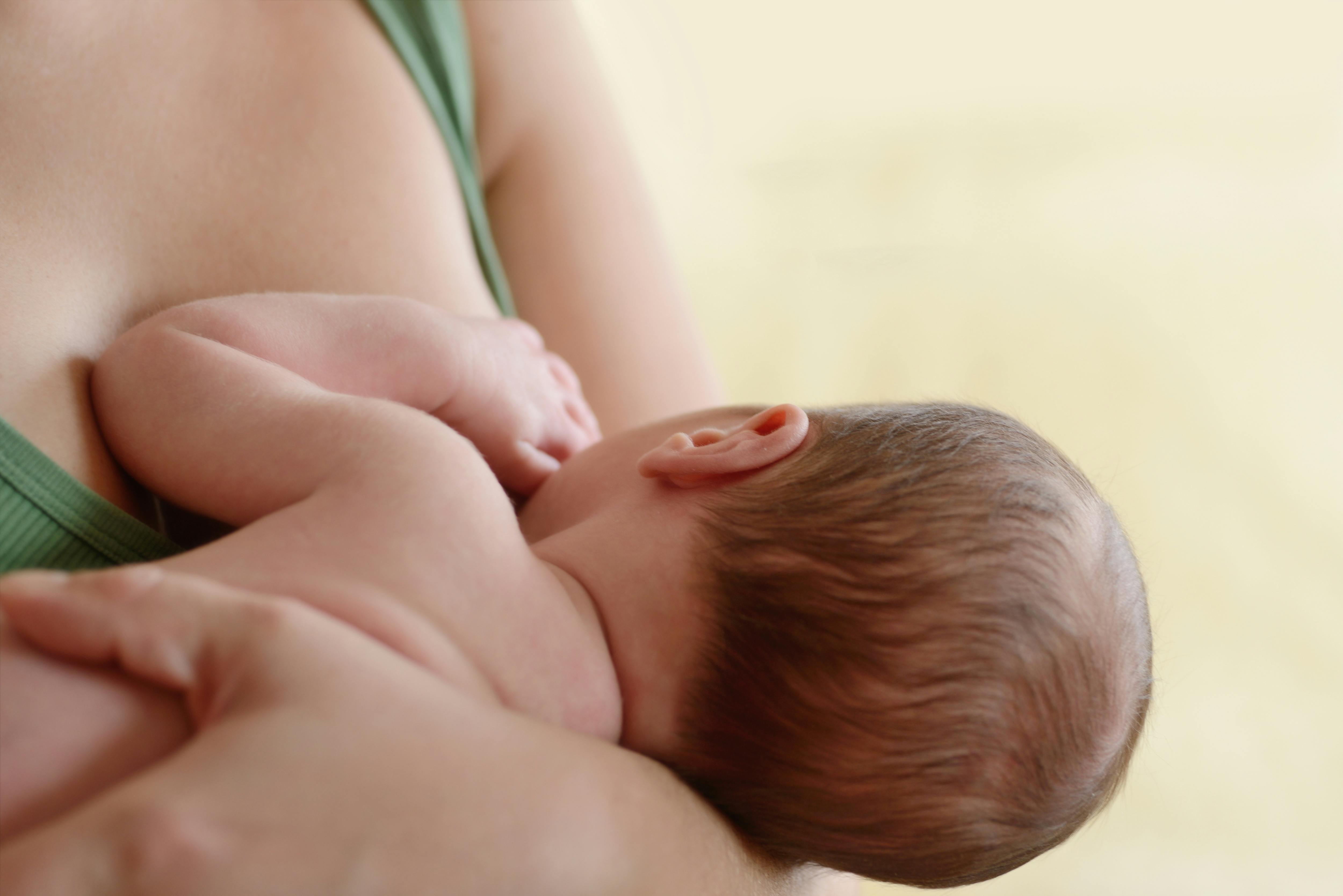 Mother holding and feeding newborn baby soft focus on the ear