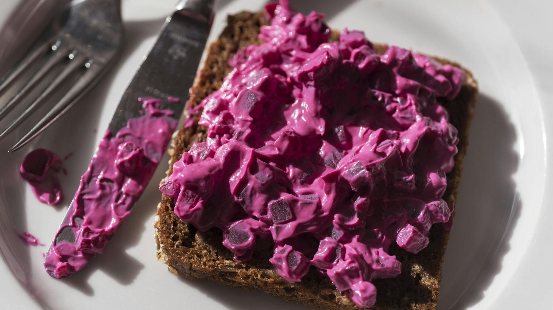 Russisk salat på rugbrødsmad på tallerken med kniv og gaffel