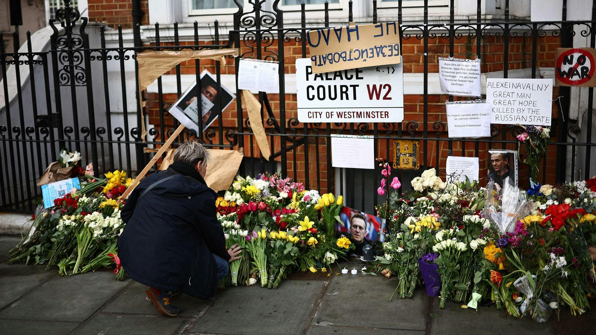 TOPSHOT - Flowers are placed beside photographs and placards opposite the Russian Embassy in London on March 1, 2024, on the day of the funeral of Russian opposition leader Alexei Navalny. The funeral of Navalny will take place in Moscow Friday, with mourners braving the risk of arrest to come and pay their respects. The ceremony comes two weeks after Navalny died in an Arctic prison -- a death that his supporters have blamed on Russian President Vladimir Putin. (Photo by HENRY NICHOLLS / AFP)