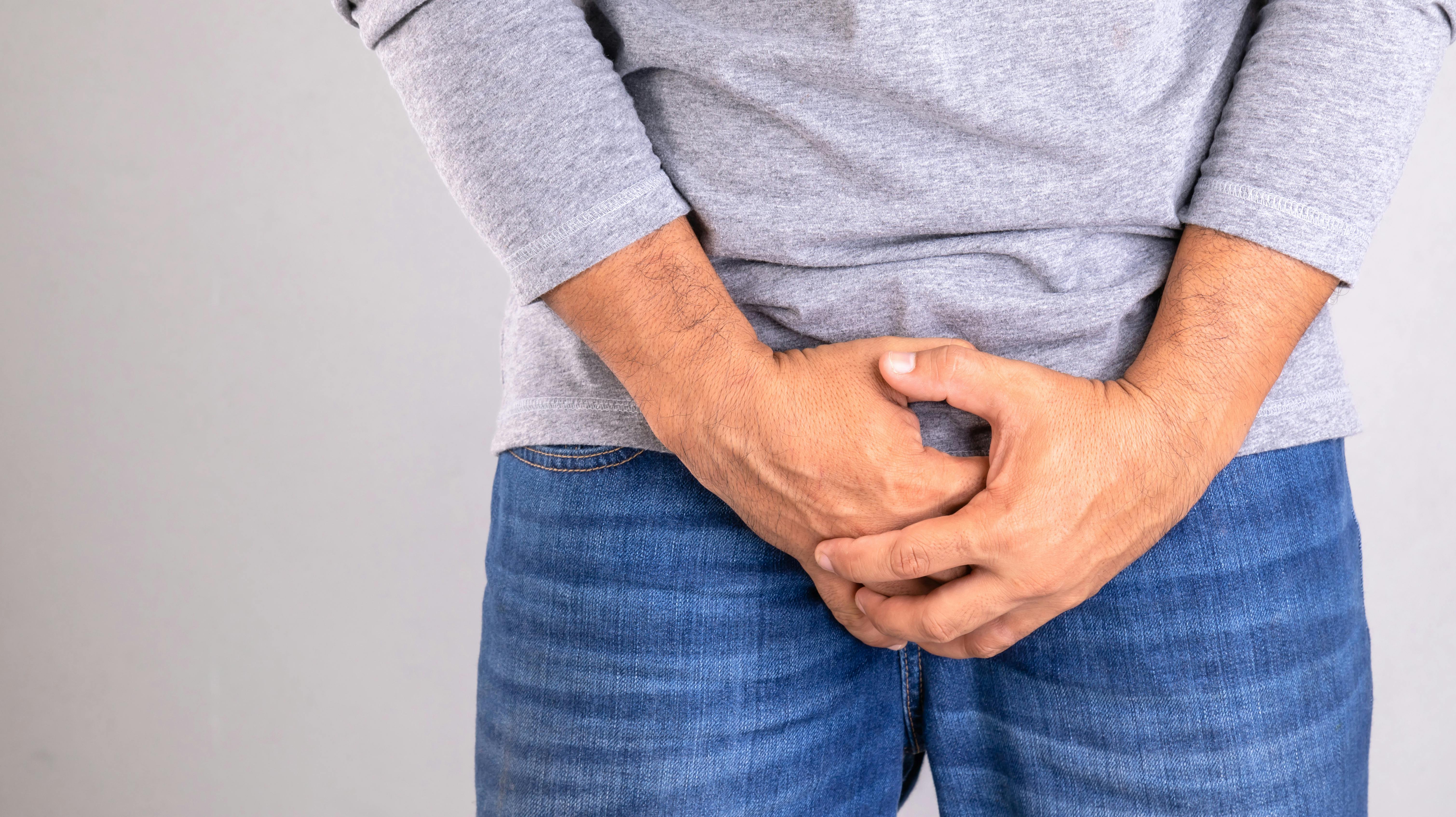 Pain on penis concept : Man use his hands to press on his penis on grey background