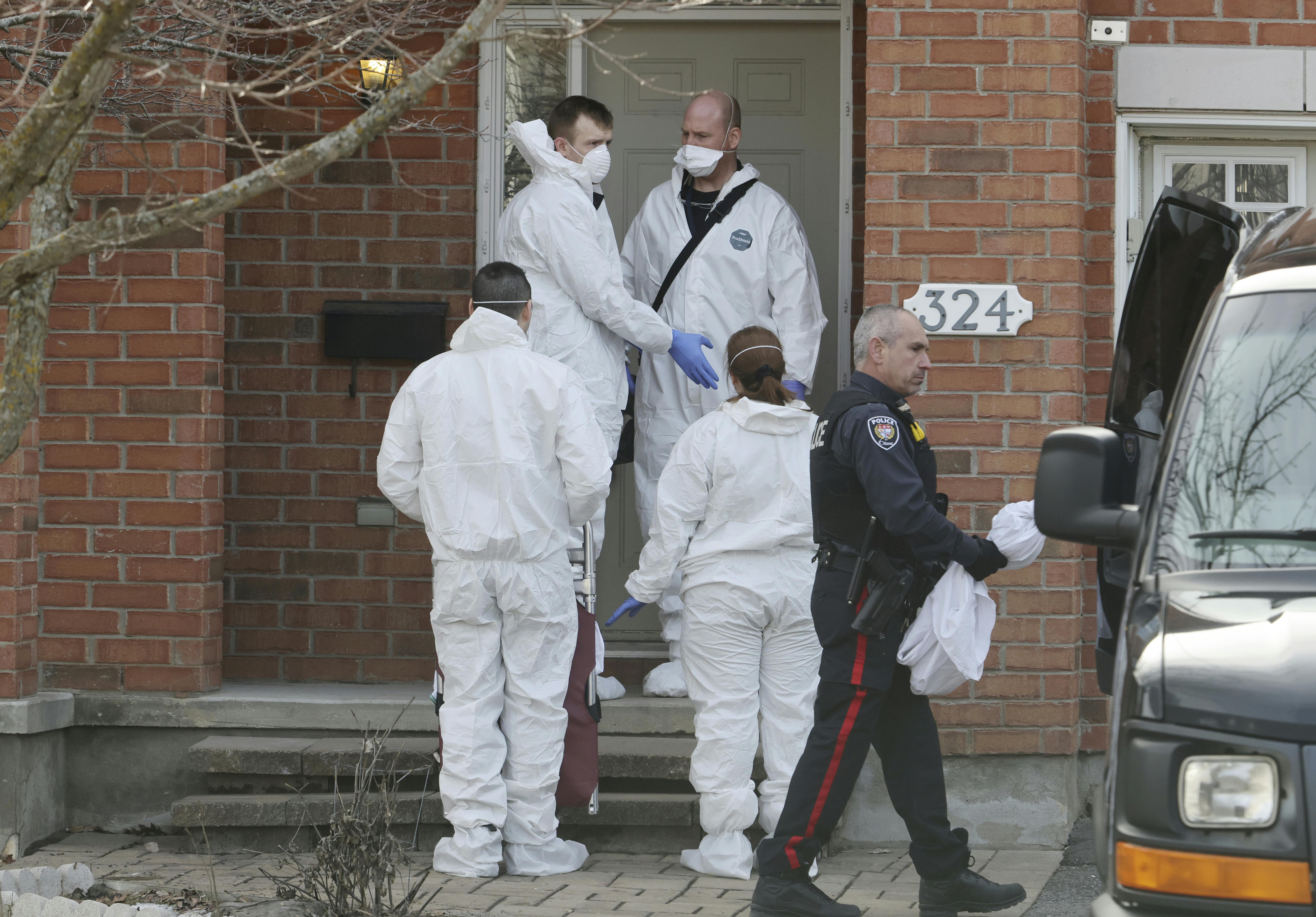 Members of the coroner's office stand outside the scene of a homicide where six people were found dead in the Barrhaven suburb of Ottawa on Thursday, March 7, 2024. (Patrick Doyle /The Canadian Press via AP)