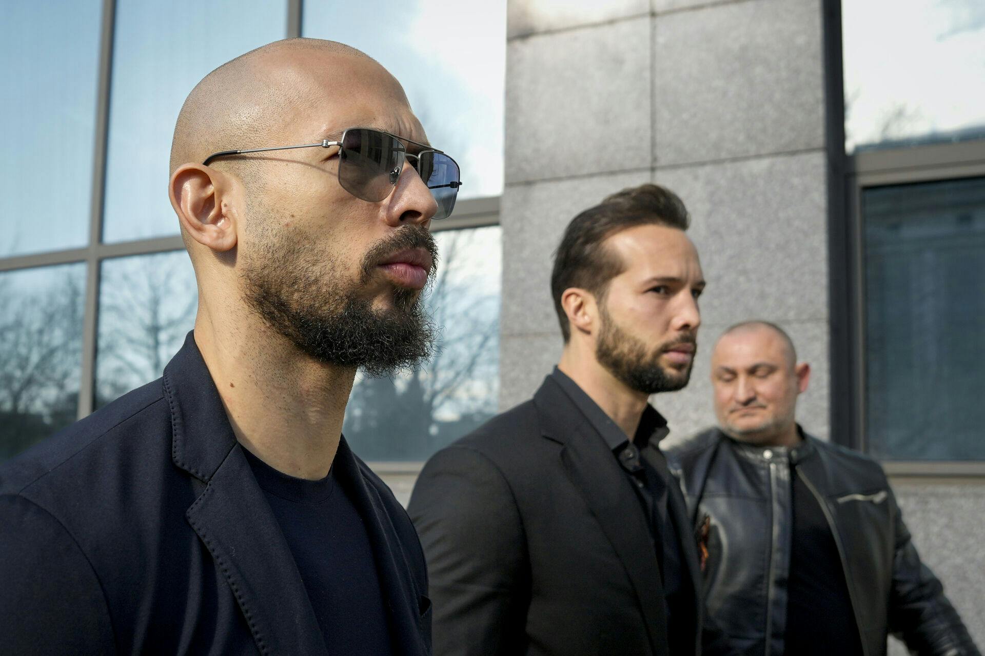 Andrew Tate, left, and his brother Tristan, center, arrive at the Bucharest Tribunal in Bucharest, Romania, Thursday, Feb. 8, 2024. (AP Photo/Andreea Alexandru)