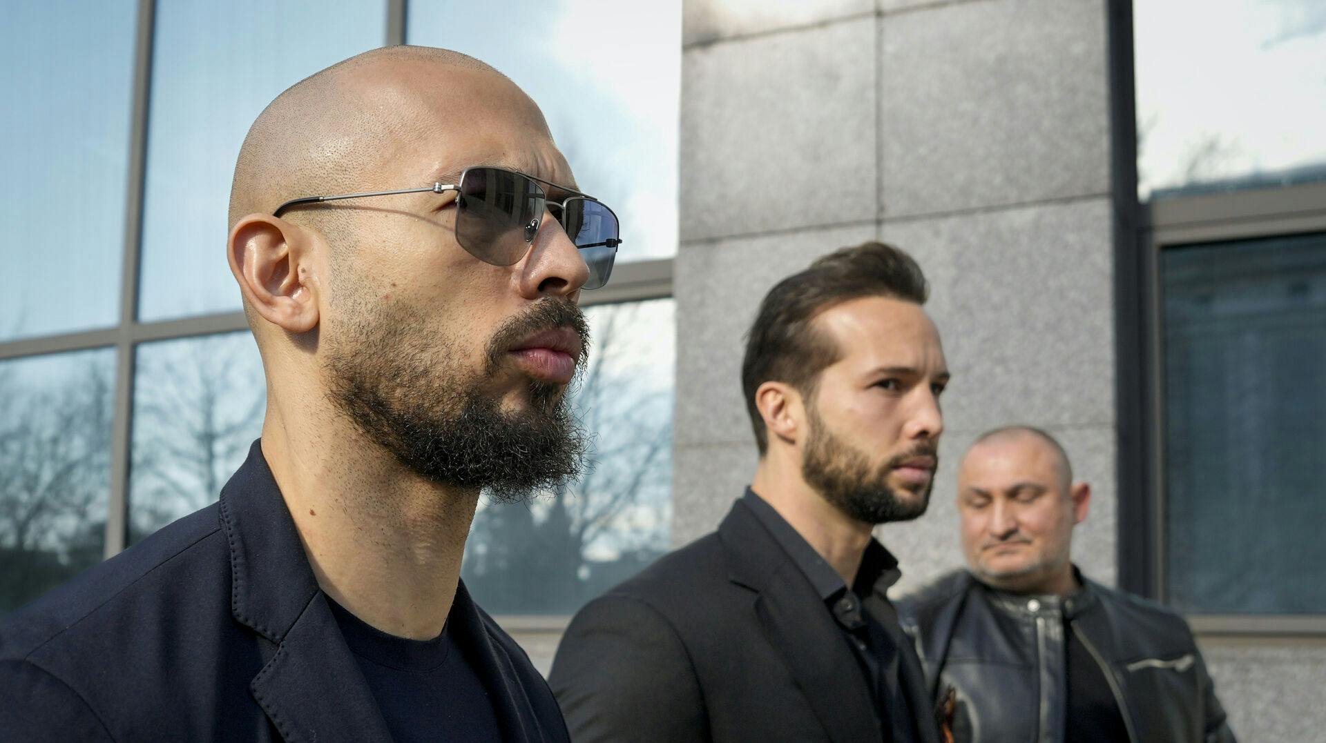 Andrew Tate, left, and his brother Tristan, center, arrive at the Bucharest Tribunal in Bucharest, Romania, Thursday, Feb. 8, 2024. (AP Photo/Andreea Alexandru)