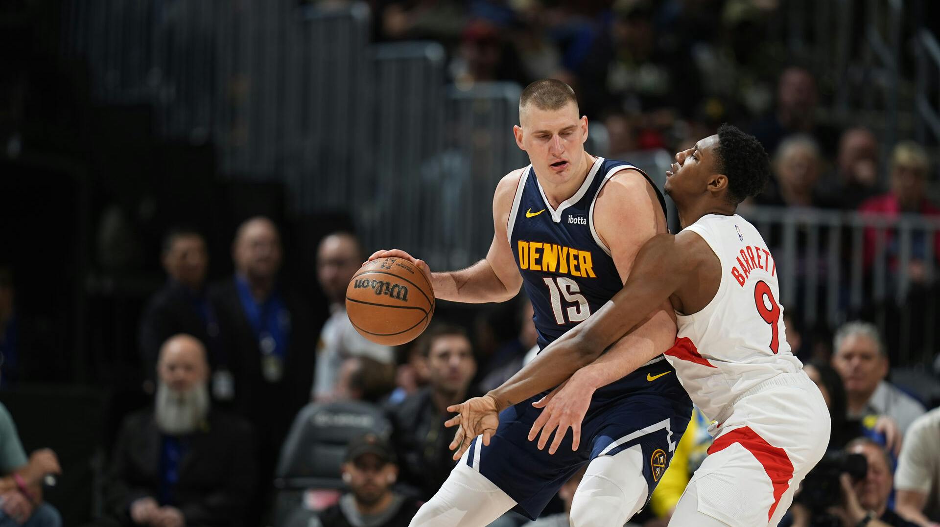 Denver Nuggets center Nikola Jokic (15) and Toronto Raptors guard RJ Barrett (9) in the second half of an NBA basketball game Monday, March 11, 2024, in Denver. (AP Photo/David Zalubowski)