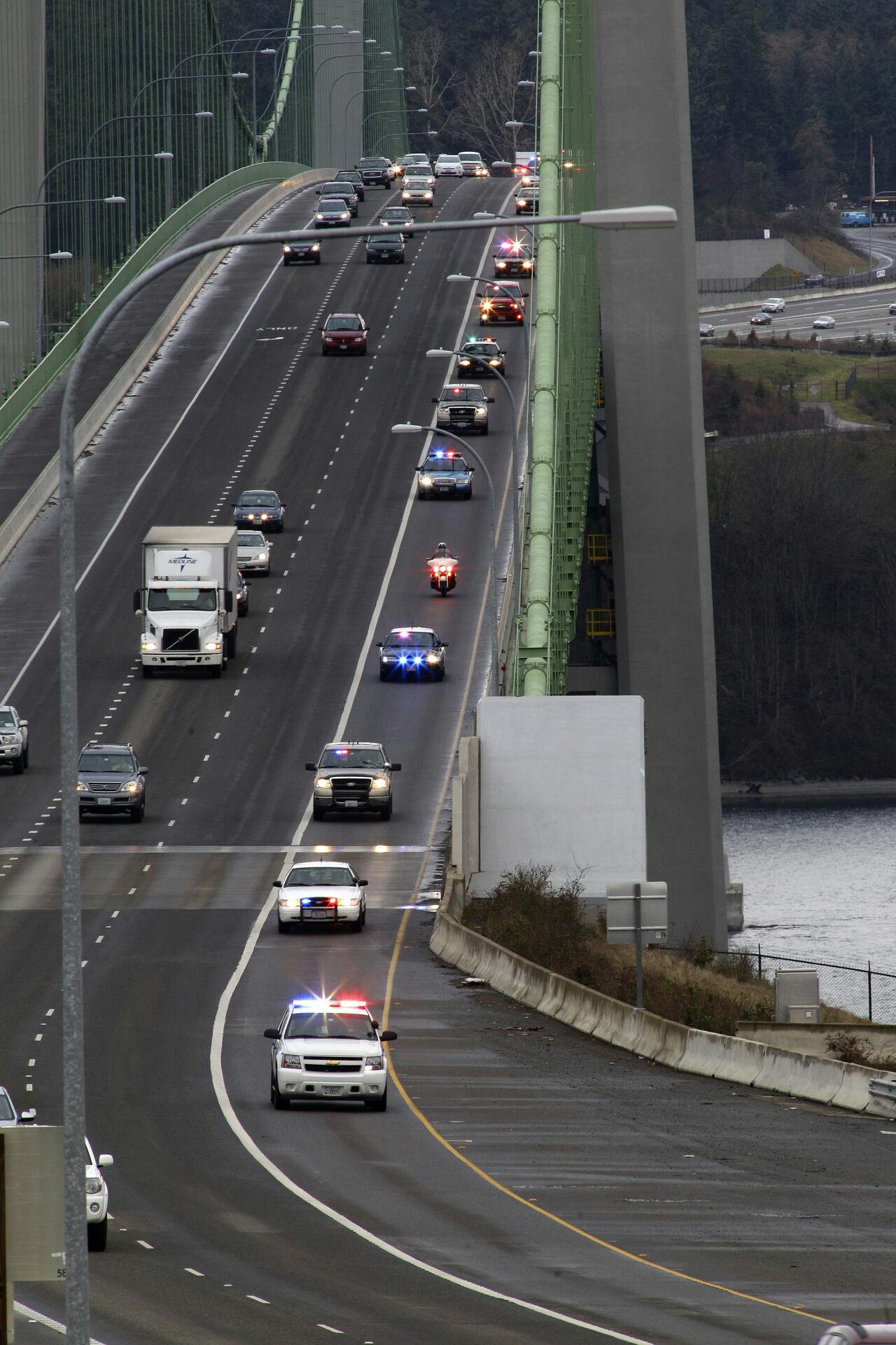 A procession of law-enforcement vehicles makes its way over the Tacoma Narrows Bridge, Thursday, March 1, 2012, in Tacoma, Wash., as they travel toward the memorial service for Washington State Trooper Tony Radulescu, who was shot and killed last week during a traffic stop in Gorst, Wash. (AP Photo/Ted S. Warren)