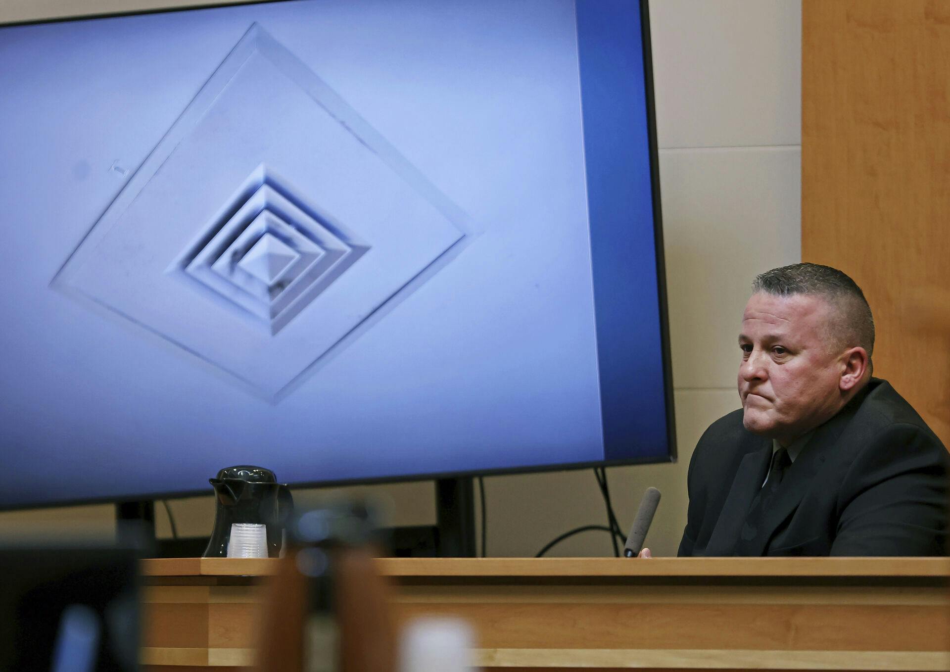 Scott Riley testifies in front of a photo of a vent on the ceiling of Unit 1 at the Families in Transition Shelter at the trial of Adam Montgomery who is charged with murdering his five-year-old daughter Harmony, at the Hillsborough County Superior Court Wednesday, Feb. 14, 2024, in Manchester, N.H. Riley investigated the crime as a member of the Manchester Police Department. (Jim Davis/The Boston Globe via AP, Pool)