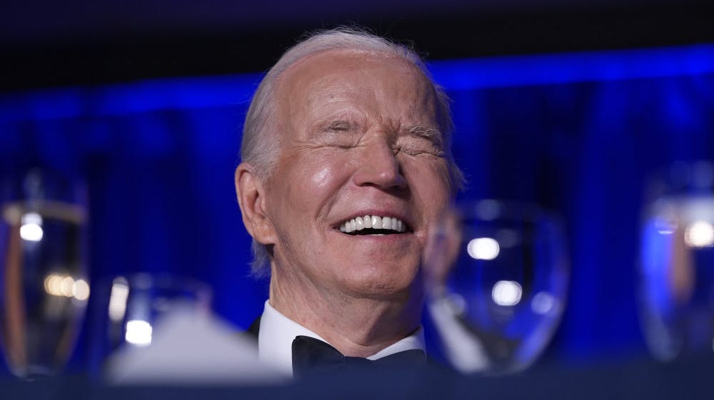Præsident Joe Biden griner her af en vits, som middagens toastmaster, Colin Jost, der til dagligt er vært på programmet "Saturday Night Live", har fortalt ham.
