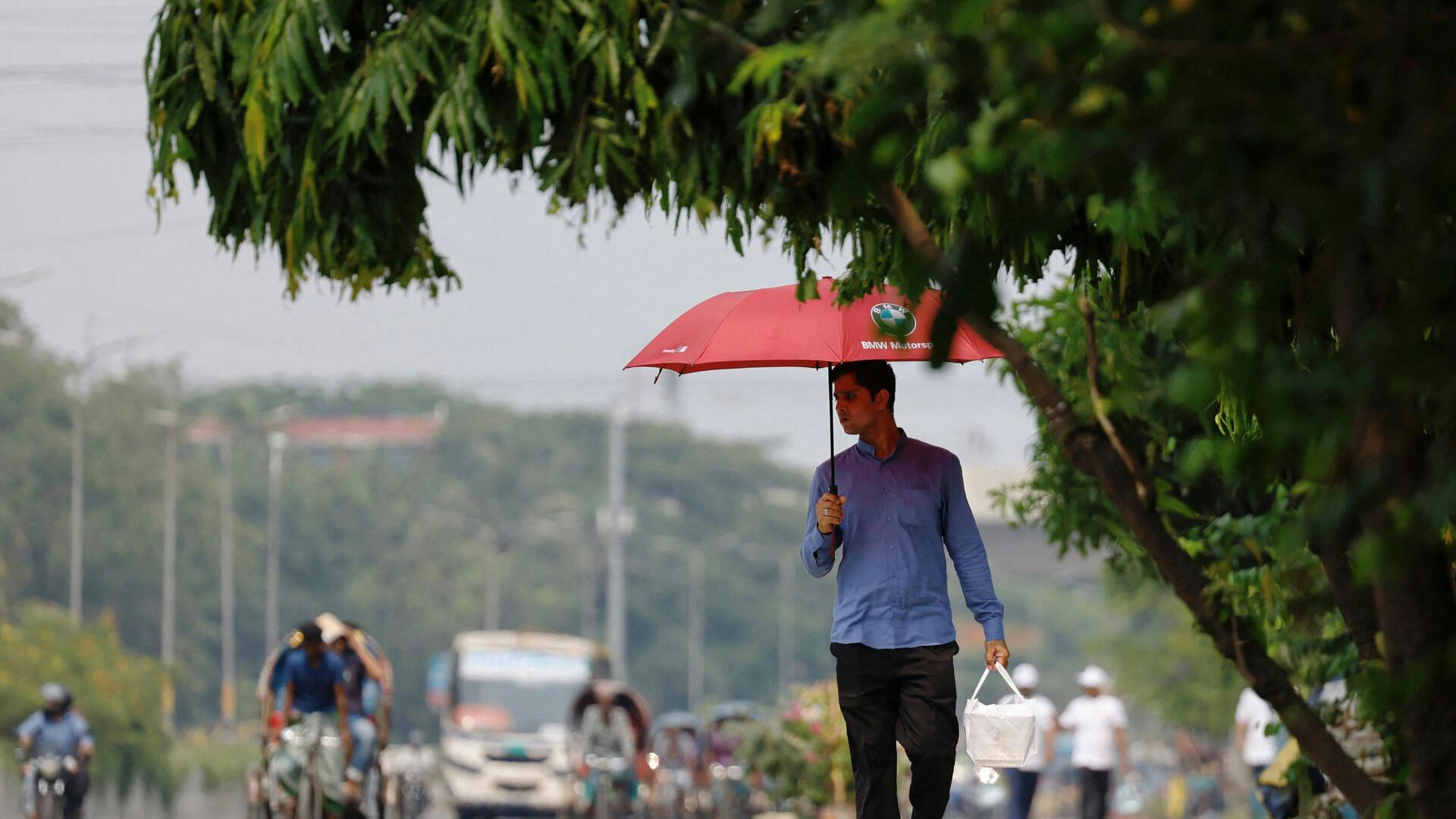 A man walks along a road with an umbrella to cover himself from the sun during a countrywide heatwave in Dhaka, Bangladesh, April 28, 2024. REUTERS/Mohammad Ponir Hossain