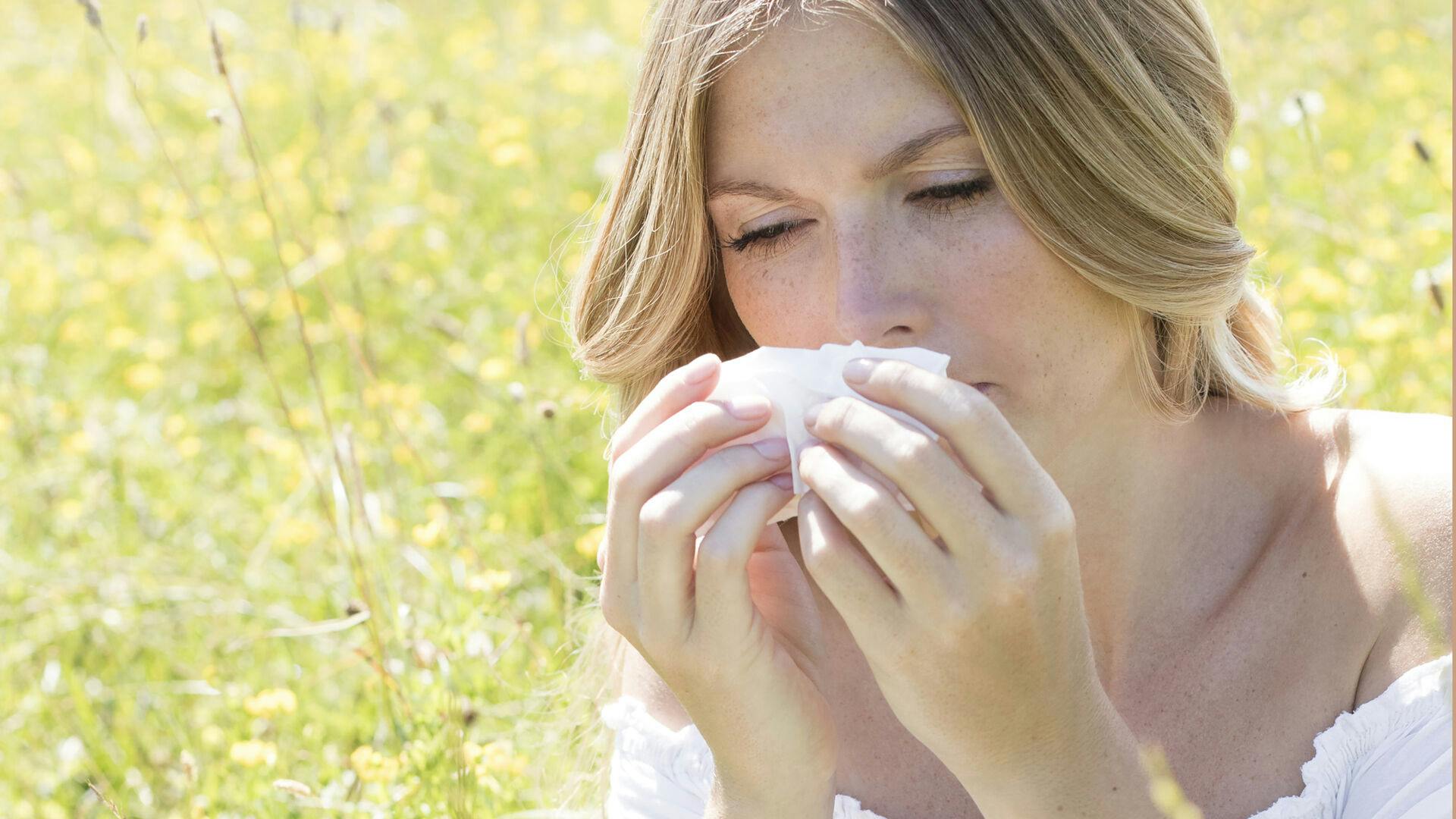 MODEL RELEASED. Young woman blowing nose on tissue. Keywords: one person, young women, women, 20s, 20-24 years, portrait, blowing nose, tissue, common cold, summer, hay fever, allergy, allergies, plants, female, illness, abnormal, unwell, healthcare, medicine, twenties, medical