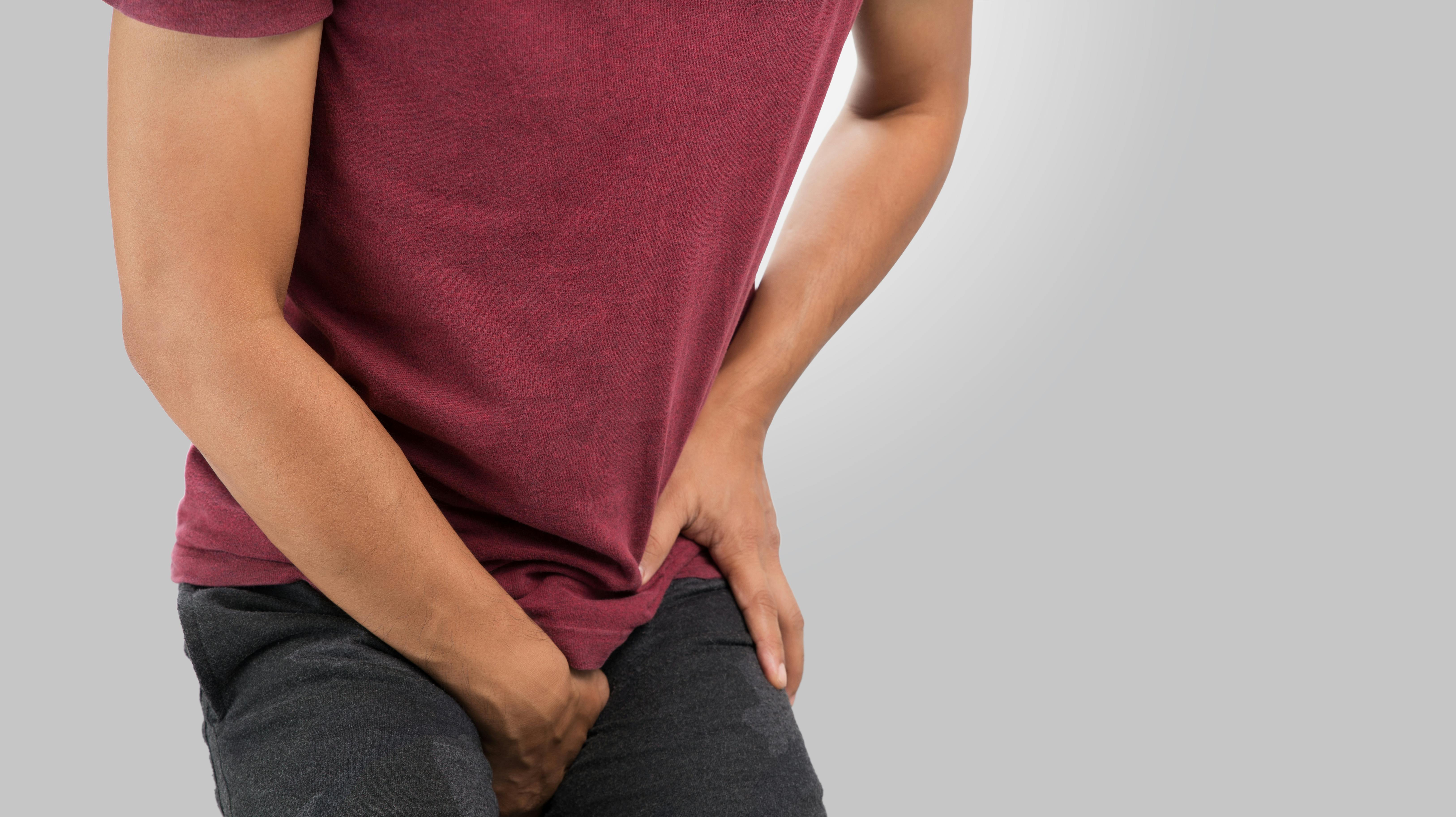 The man having groin pain on a gray background. Copy space on the right.