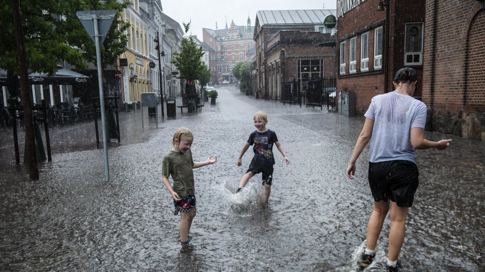 Drenge i regnen på den oversvømmede Frederiksgade i Svendborg på Fyn, mandag den 26. juni 2023. 