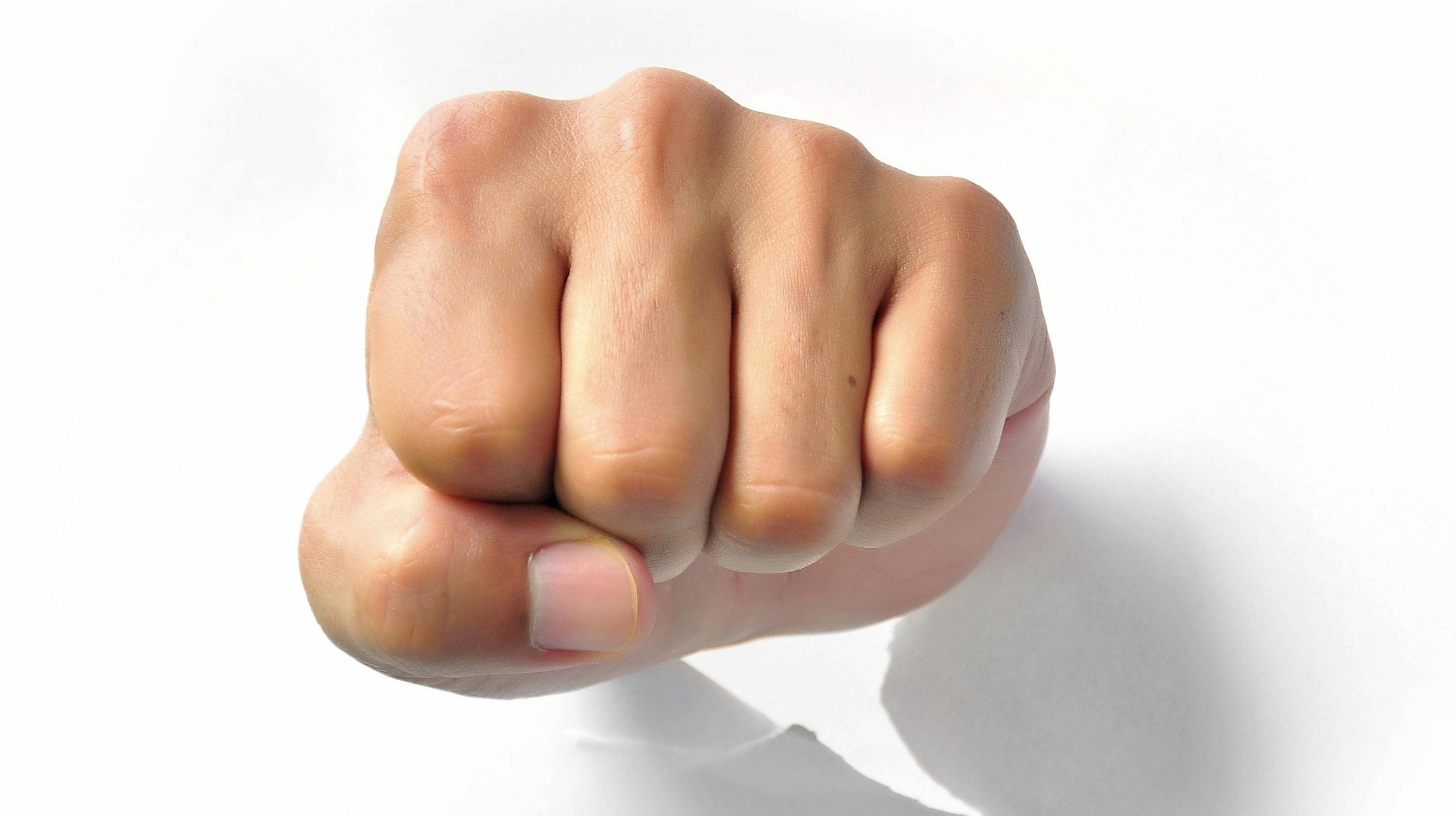 Fist punching paper isolated on white background