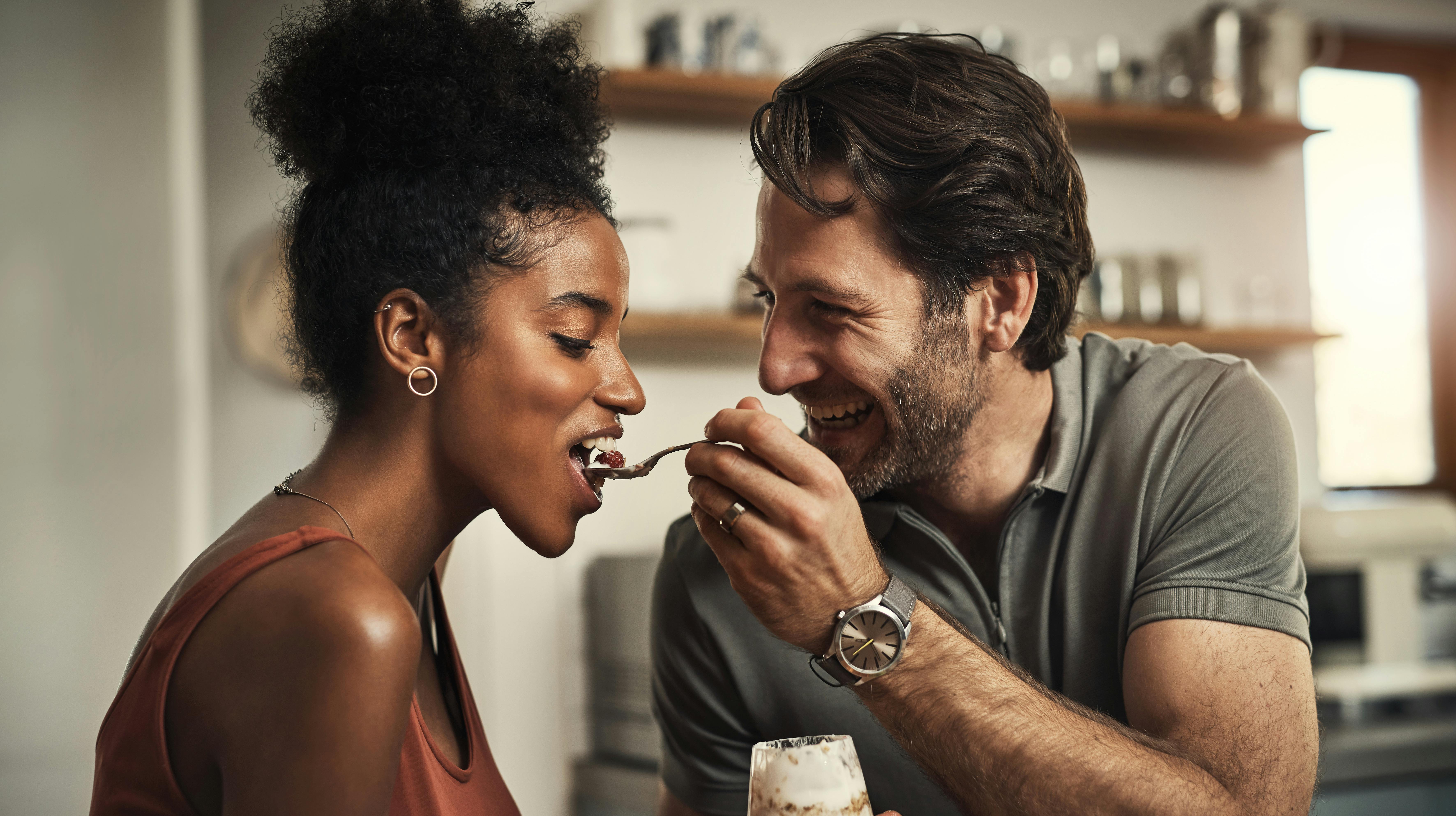 Cropped shot of an affectionate middle aged man feeding his wife dessert in their kitchen at home