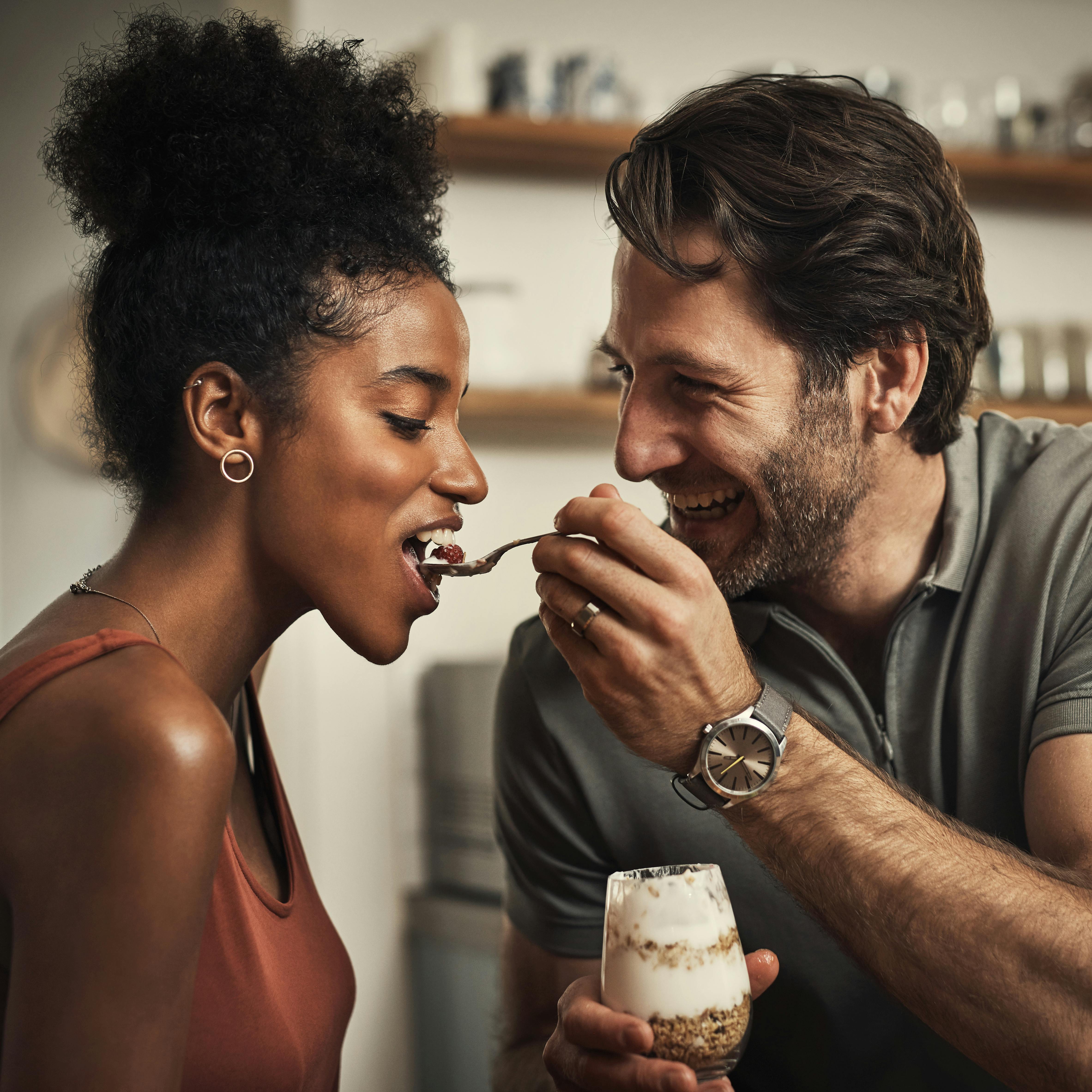 Cropped shot of an affectionate middle aged man feeding his wife dessert in their kitchen at home