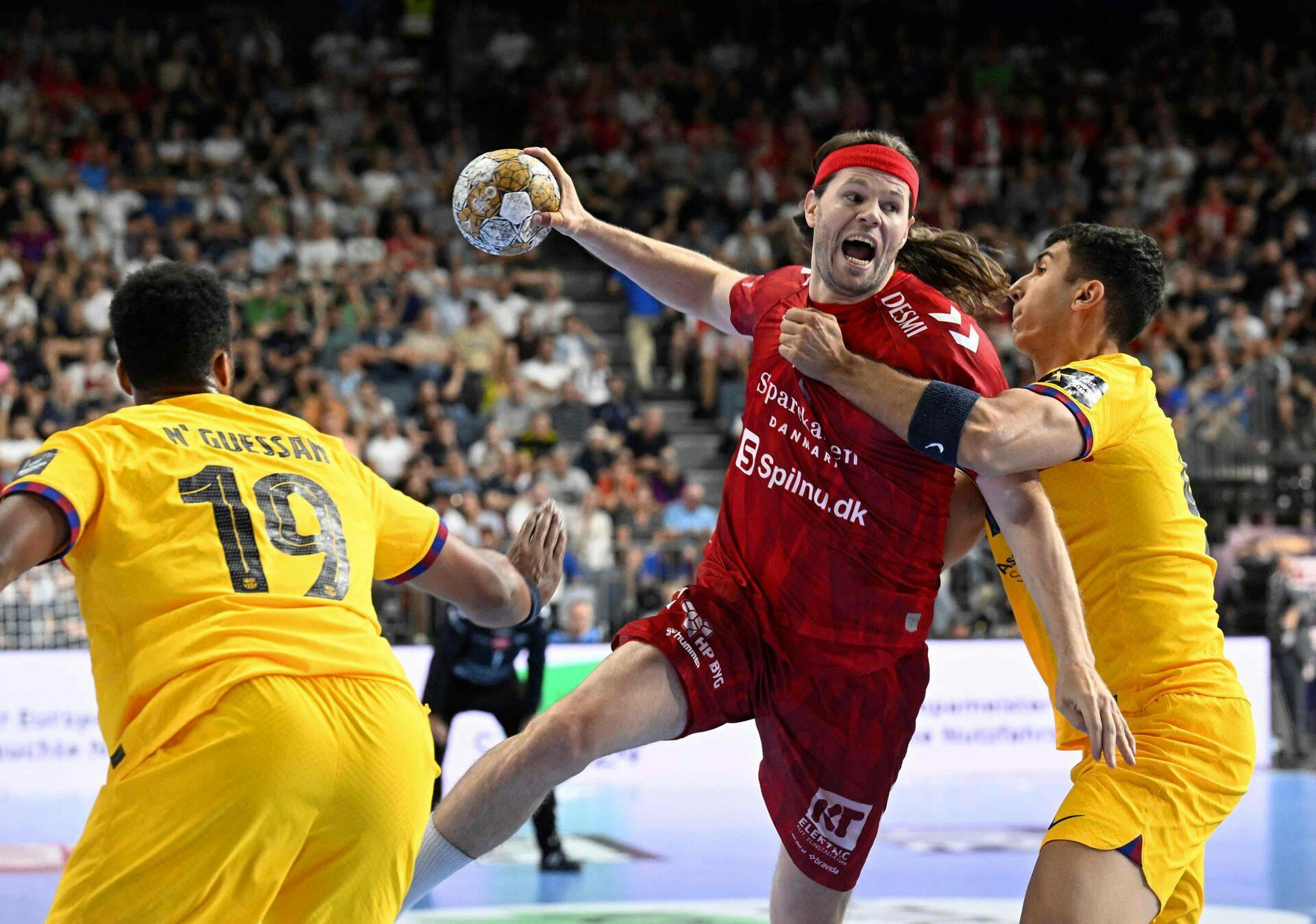 Barca's Timothey N'Guessan (L) and Barca's Blaz Janc (R) vie with Aalborg's Mikkel Hansen during the men's EHF Champions league Final 4 Handball final match Aalborg vs Barca in Cologne, western Germany, on June 9, 2024. (Photo by Roberto Pfeil / AFP)