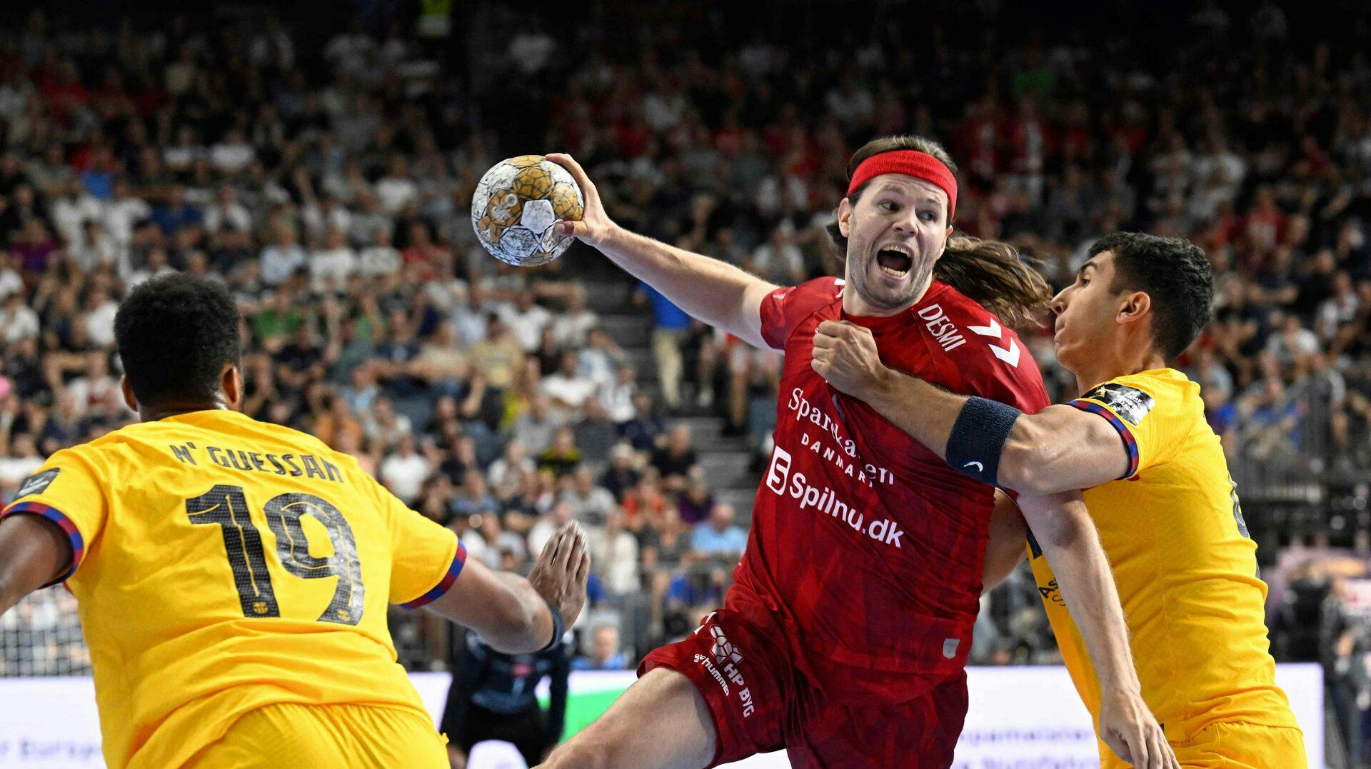 Barca's Timothey N'Guessan (L) and Barca's Blaz Janc (R) vie with Aalborg's Mikkel Hansen during the men's EHF Champions league Final 4 Handball final match Aalborg vs Barca in Cologne, western Germany, on June 9, 2024. (Photo by Roberto Pfeil / AFP)
