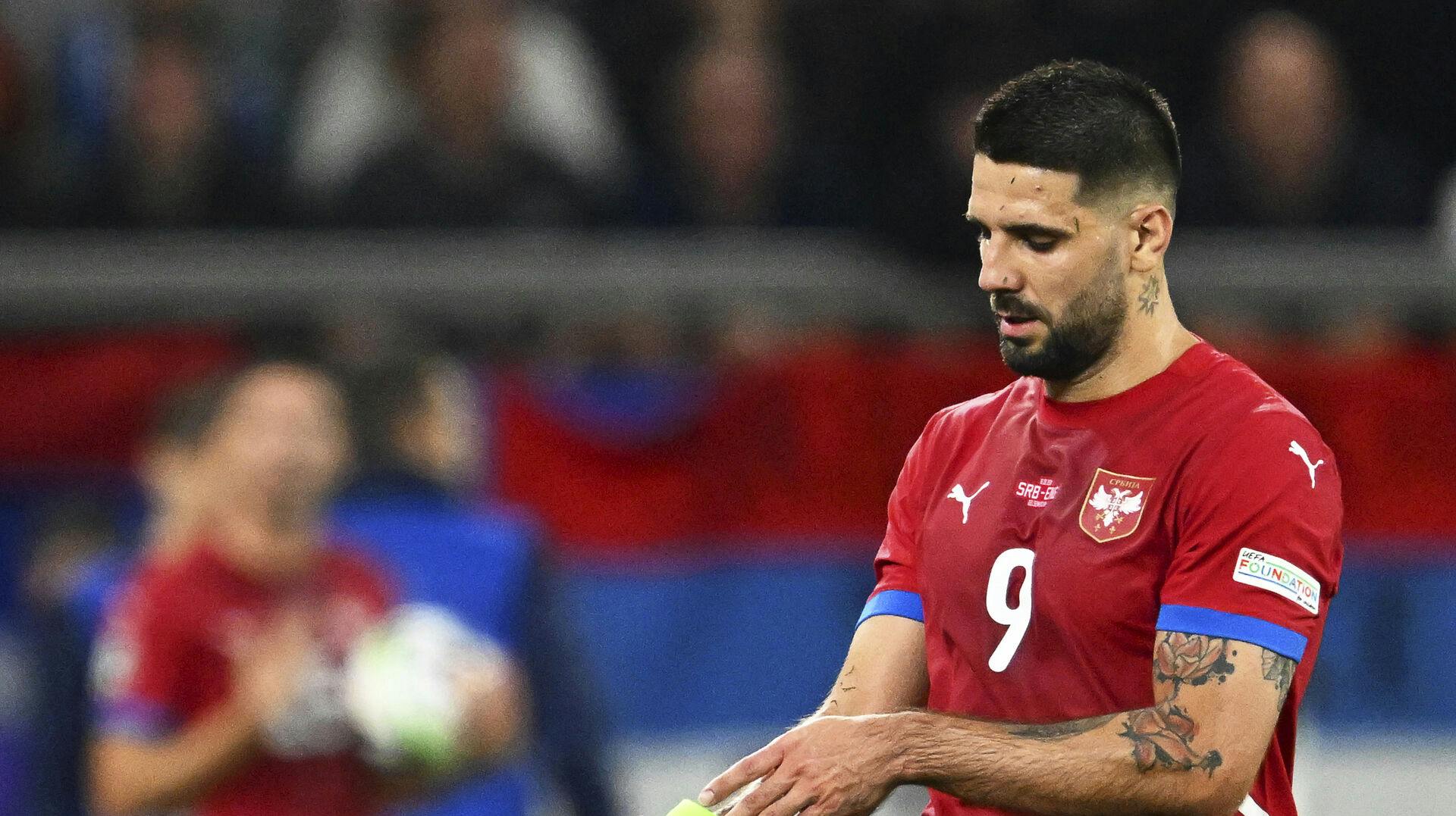 Serbiens stjerneangriber Aleksandar Mitrovic fjerner anførerbindet i kampen mod England.  