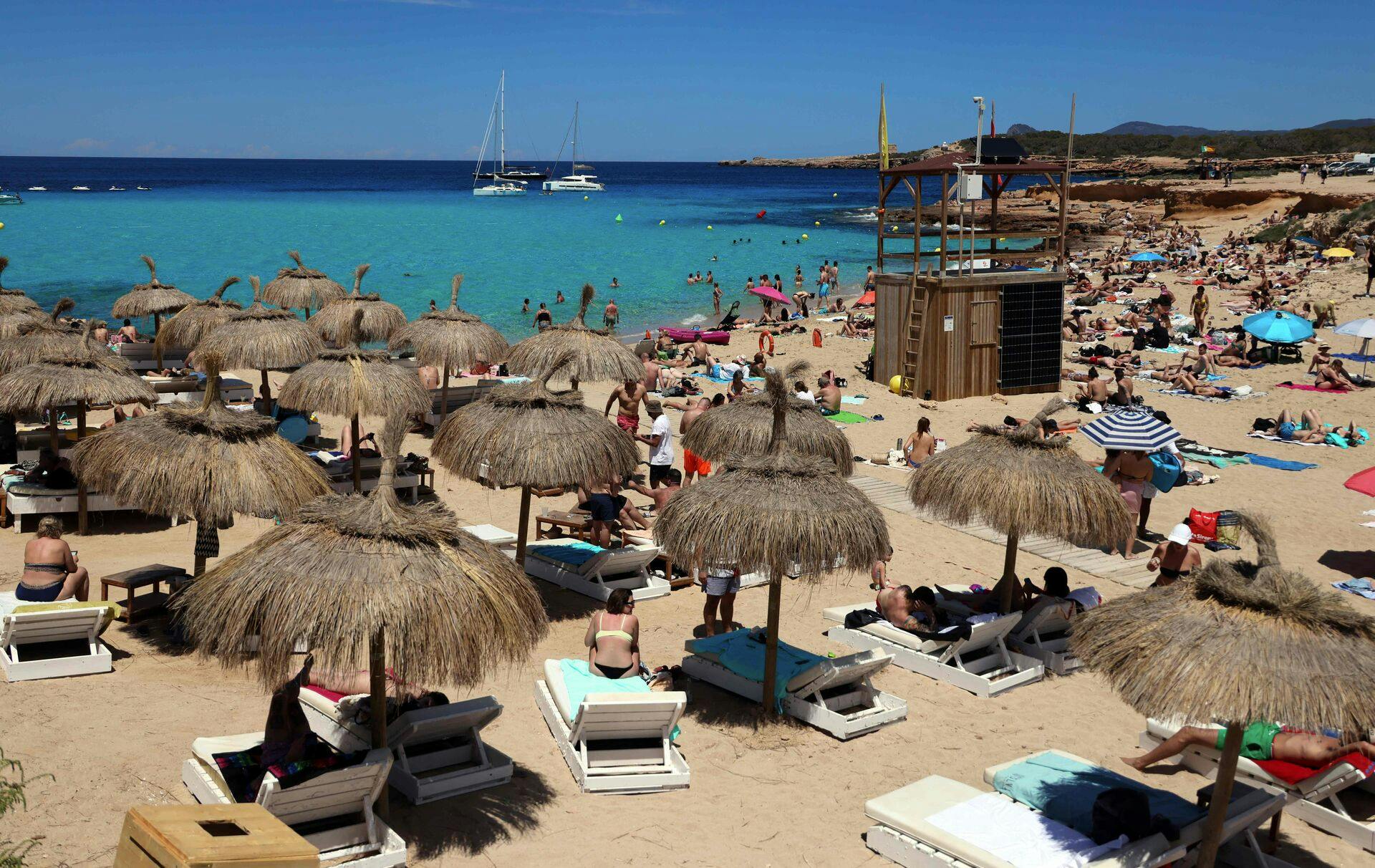 Tourists sunbath at Cala Comte (Comte beach) in Sant Josep de sa Talaia, on the Balearic island of Ibiza, on May 16, 2024. (Photo by Thomas COEX / AFP)