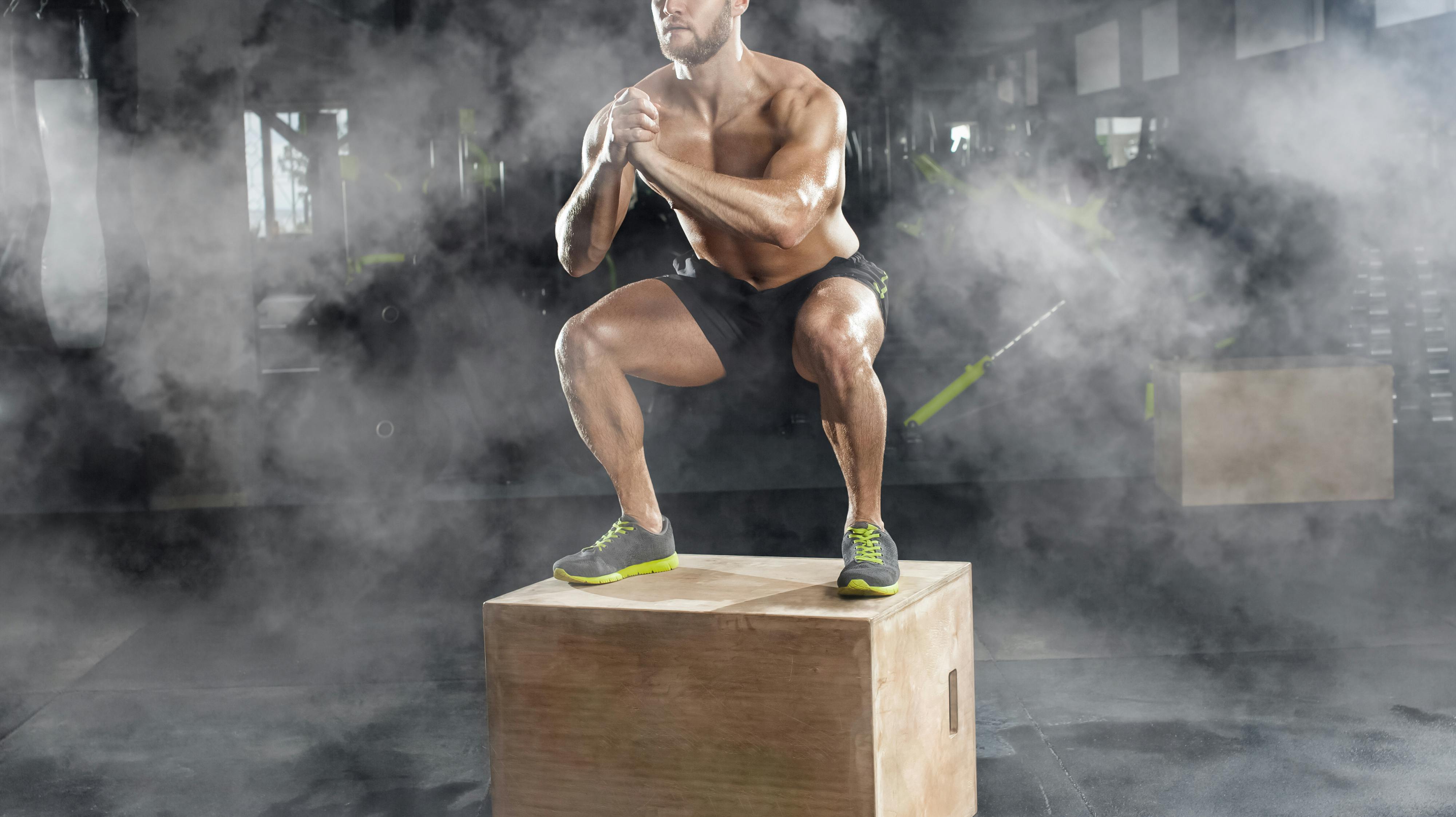 Bodybuilder man, does the cardio exercise, jumping on a wooden box in the gym. Sport concept, fat burning and a healthy lifestyle.