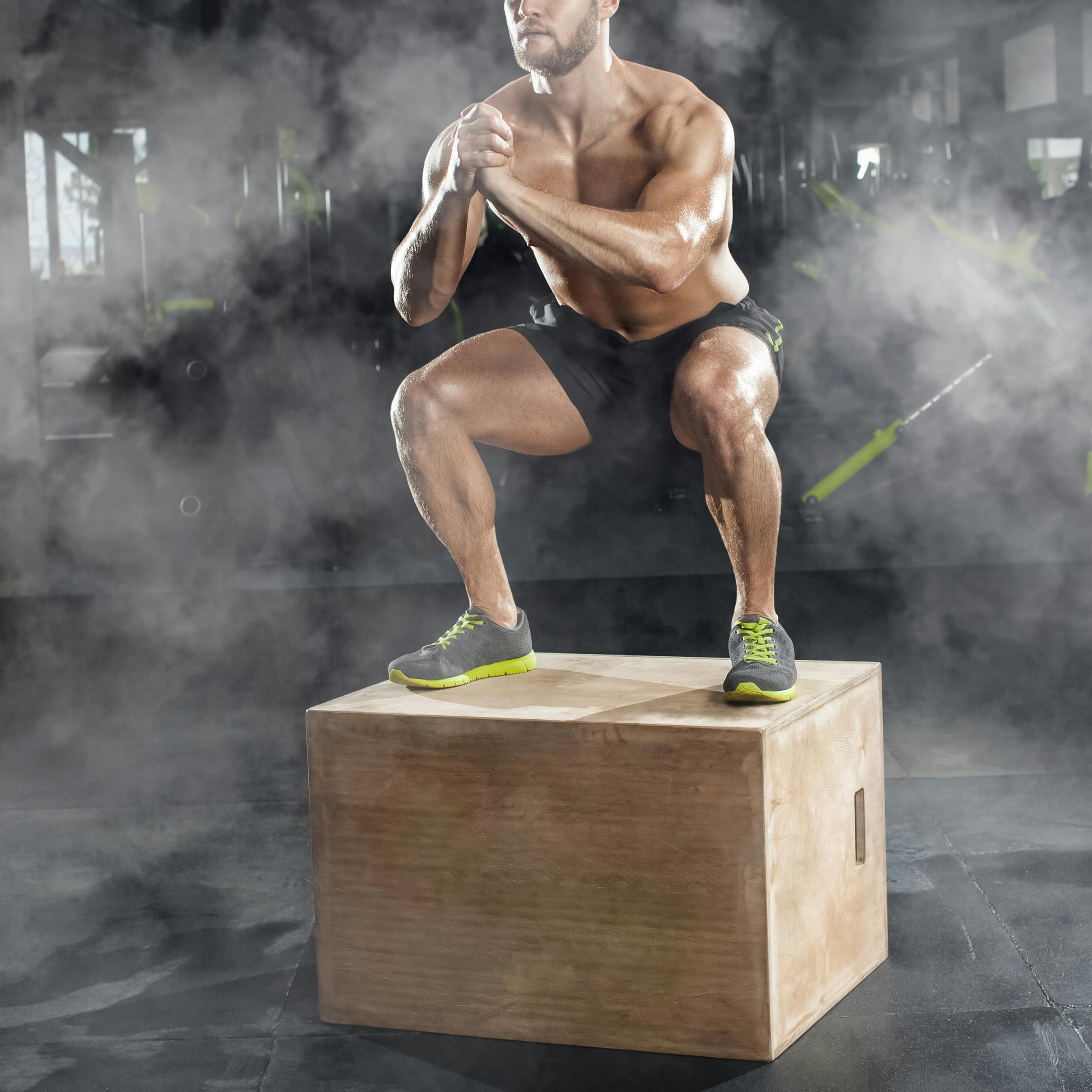 Bodybuilder man, does the cardio exercise, jumping on a wooden box in the gym. Sport concept, fat burning and a healthy lifestyle.