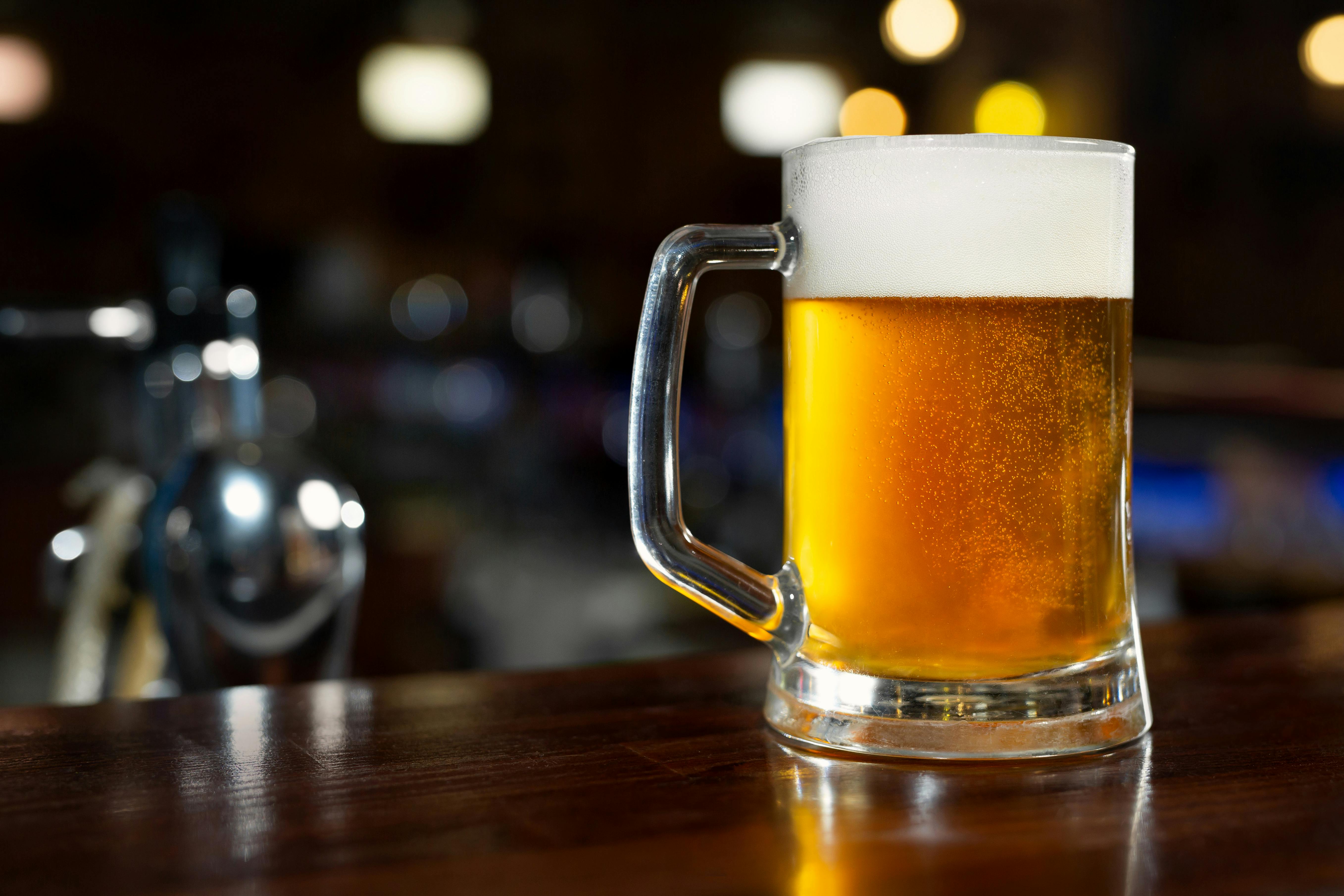 Glass of light beer on a dark pub