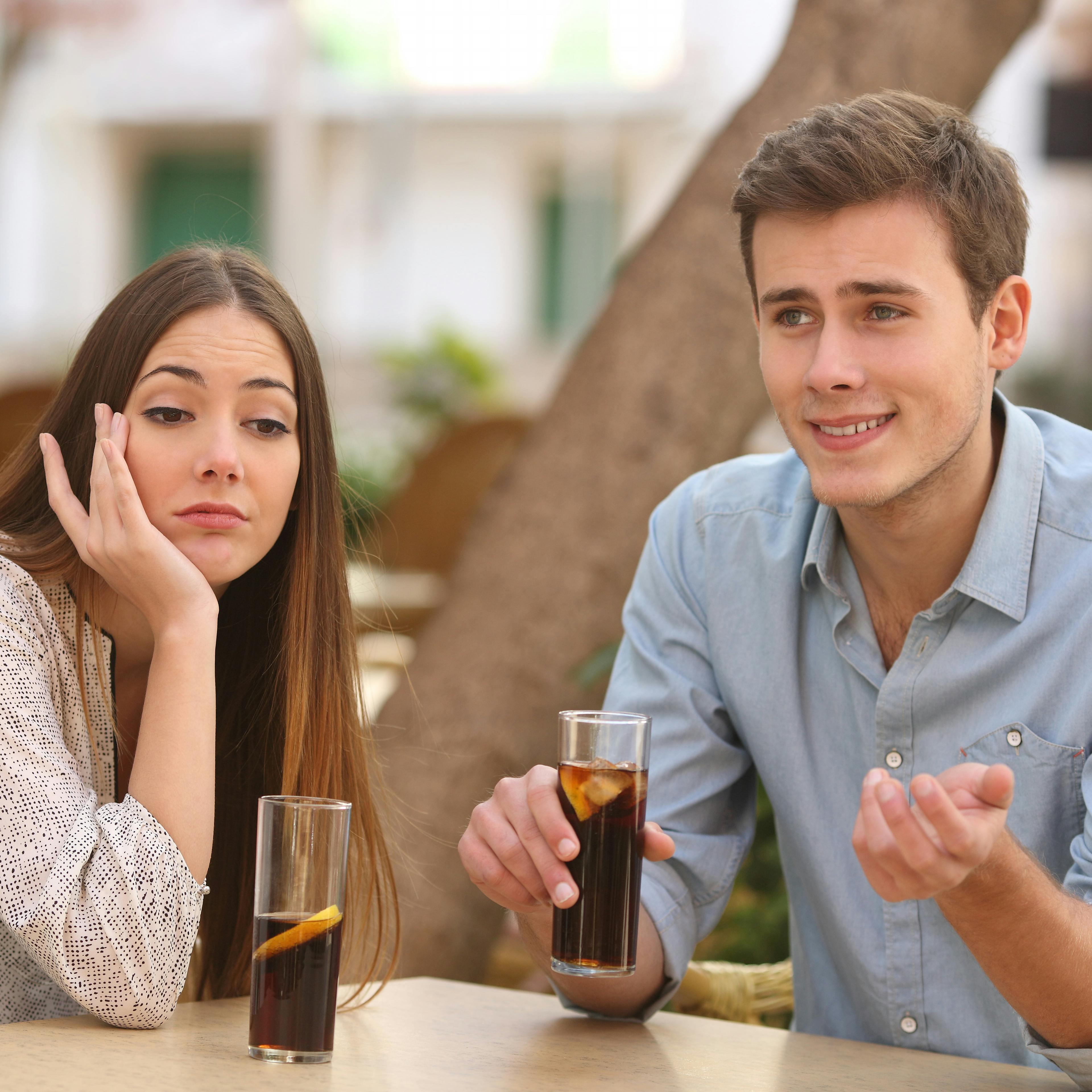 Man and woman dating in a restaurant terrace but she is boring while he speaks