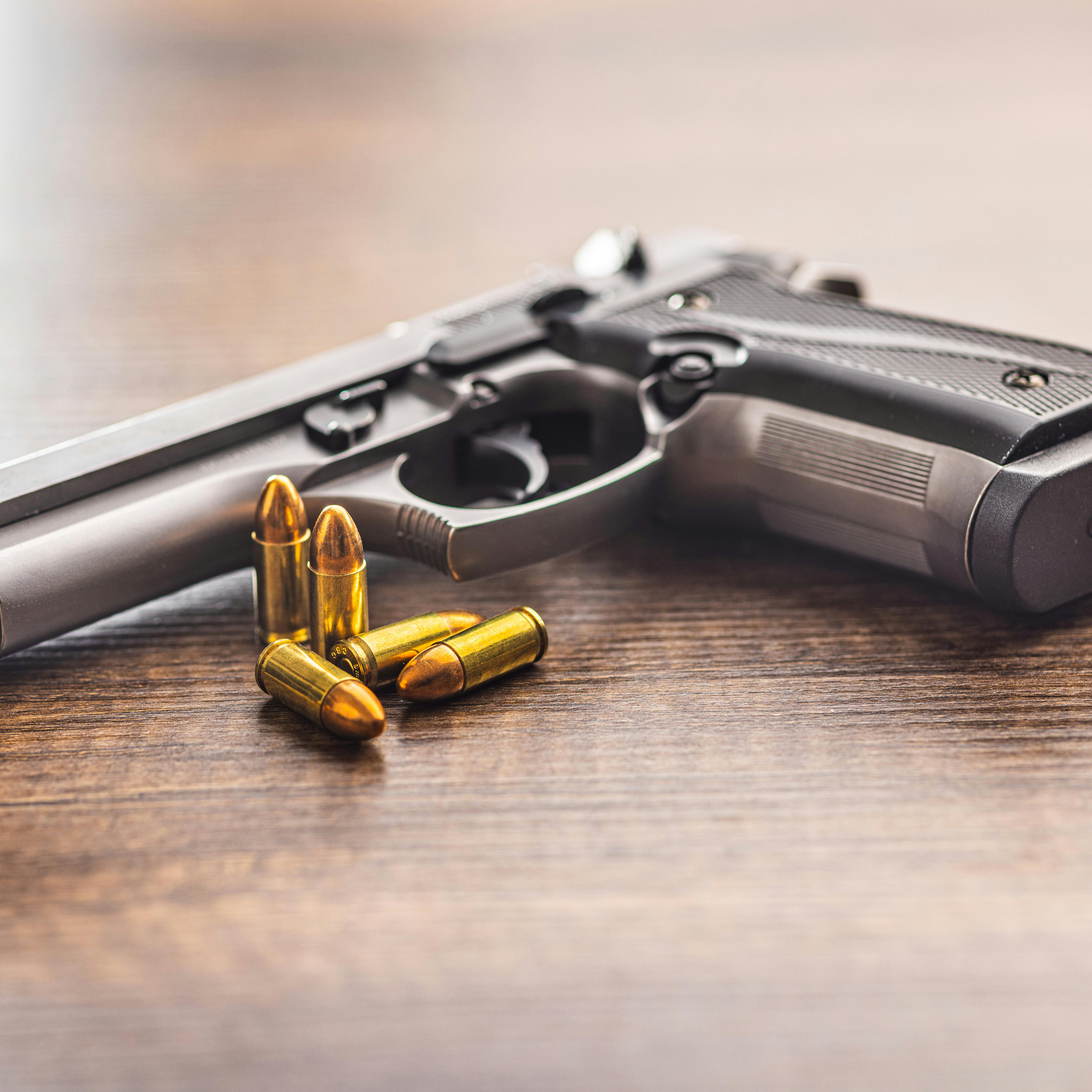Handgun and bullets on the wooden table.