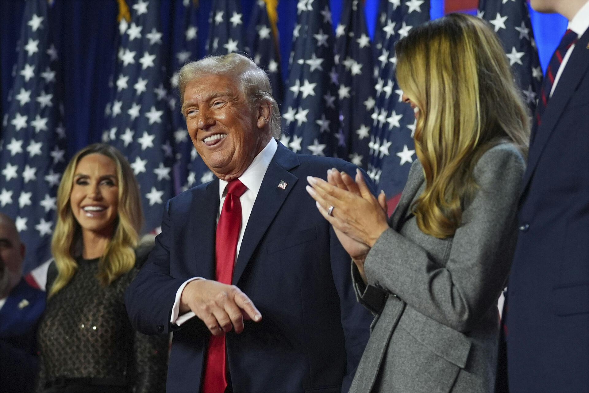 Republican presidential nominee former President Donald Trump points to former first lady Melania Trump as Lara Trump watchs, at an election night watch party at the Palm Beach Convention Center, Wednesday, Nov. 6, 2024, in West Palm Beach, Fla. (AP Photo/Evan Vucci)