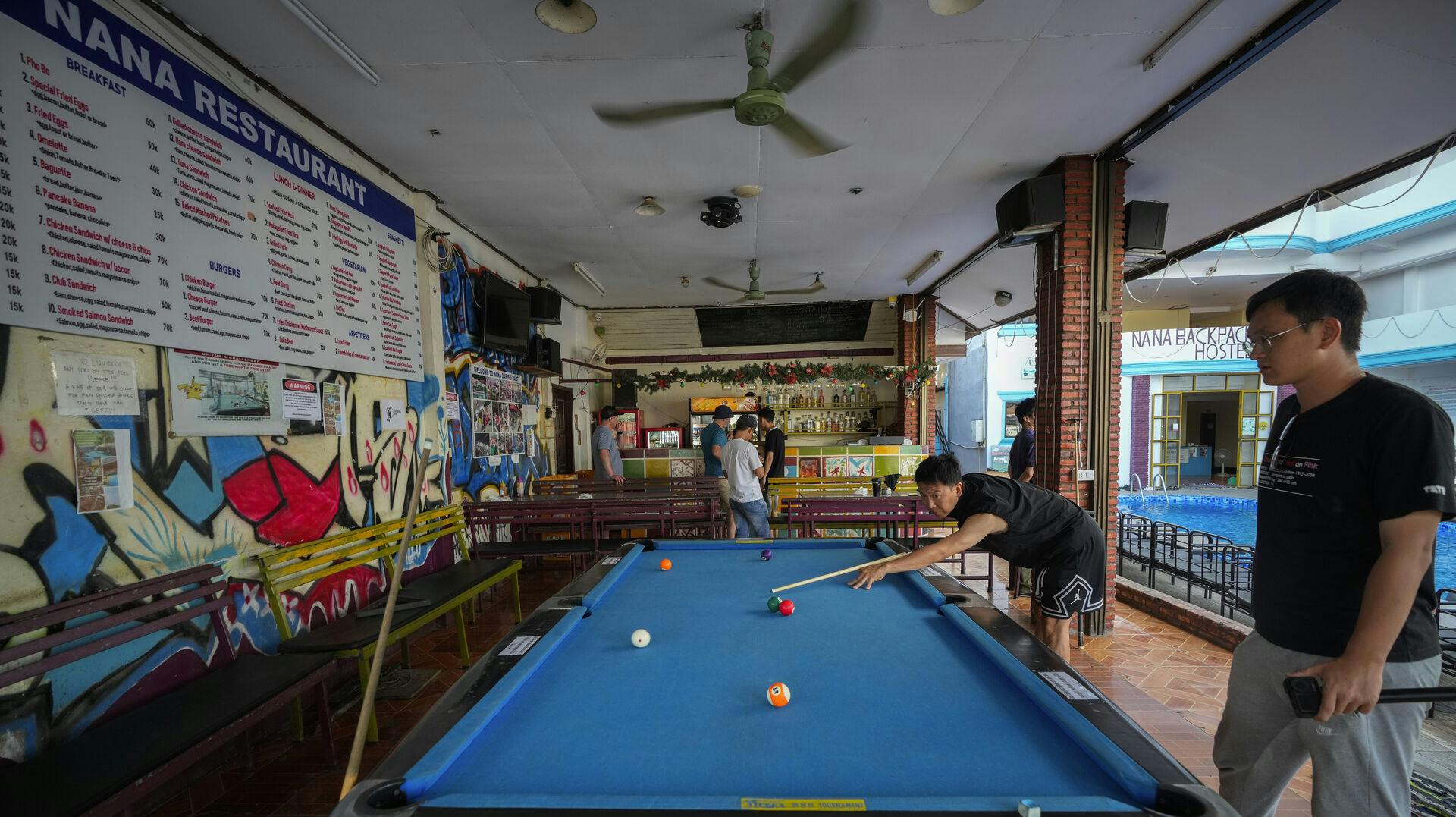 A man plays pool at Nana Backpack hostel in Vang Vieng, Laos, Tuesday, Nov. 19, 2024. (AP Photo/Anupam Nath)