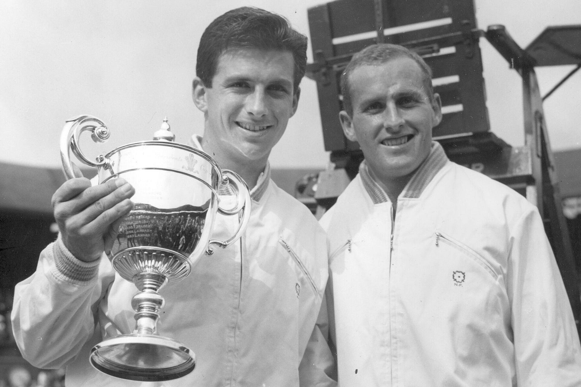 FILE - Ashley Cooper, left, holds the winner's trophy and poses with Neale Fraser after winning the men's singles championship in Wimbledon, July 4, 1958. (AP Photo, File)