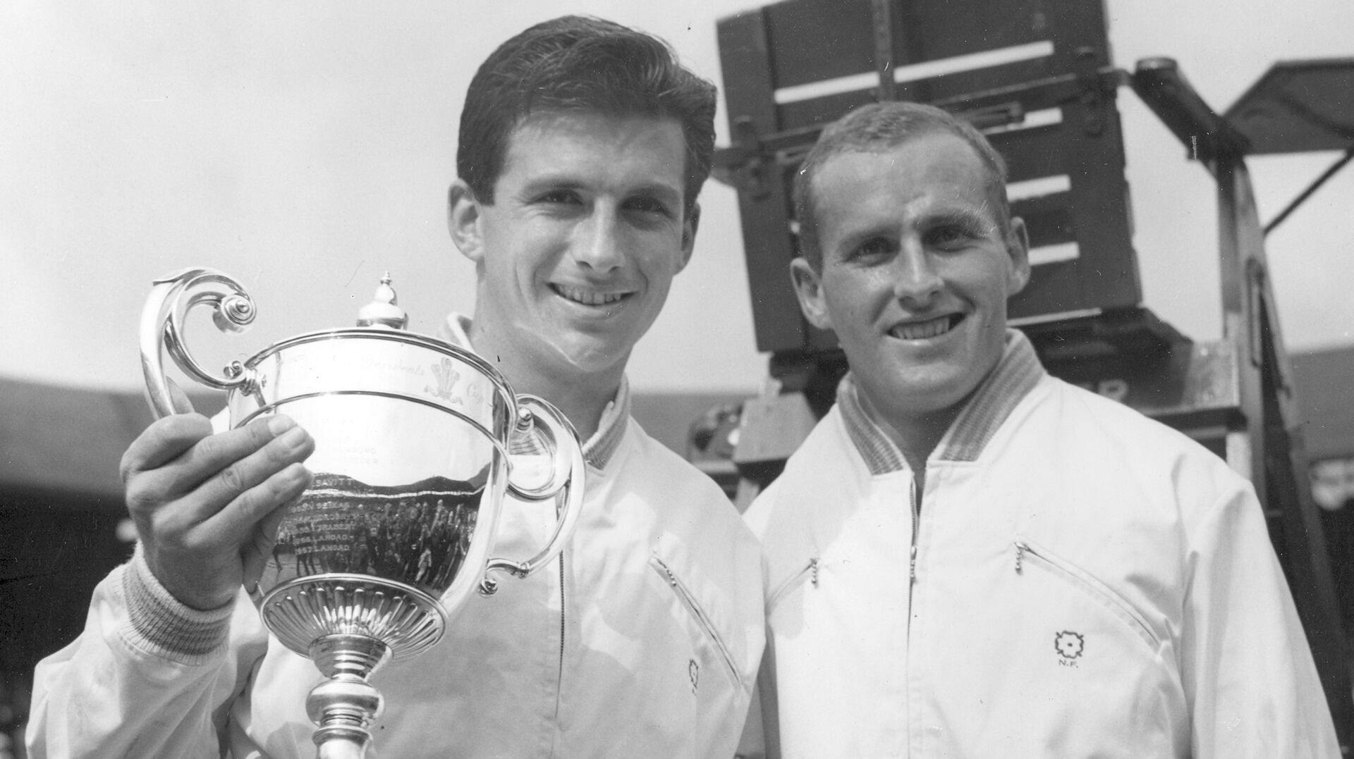FILE - Ashley Cooper, left, holds the winner's trophy and poses with Neale Fraser after winning the men's singles championship in Wimbledon, July 4, 1958. (AP Photo, File)
