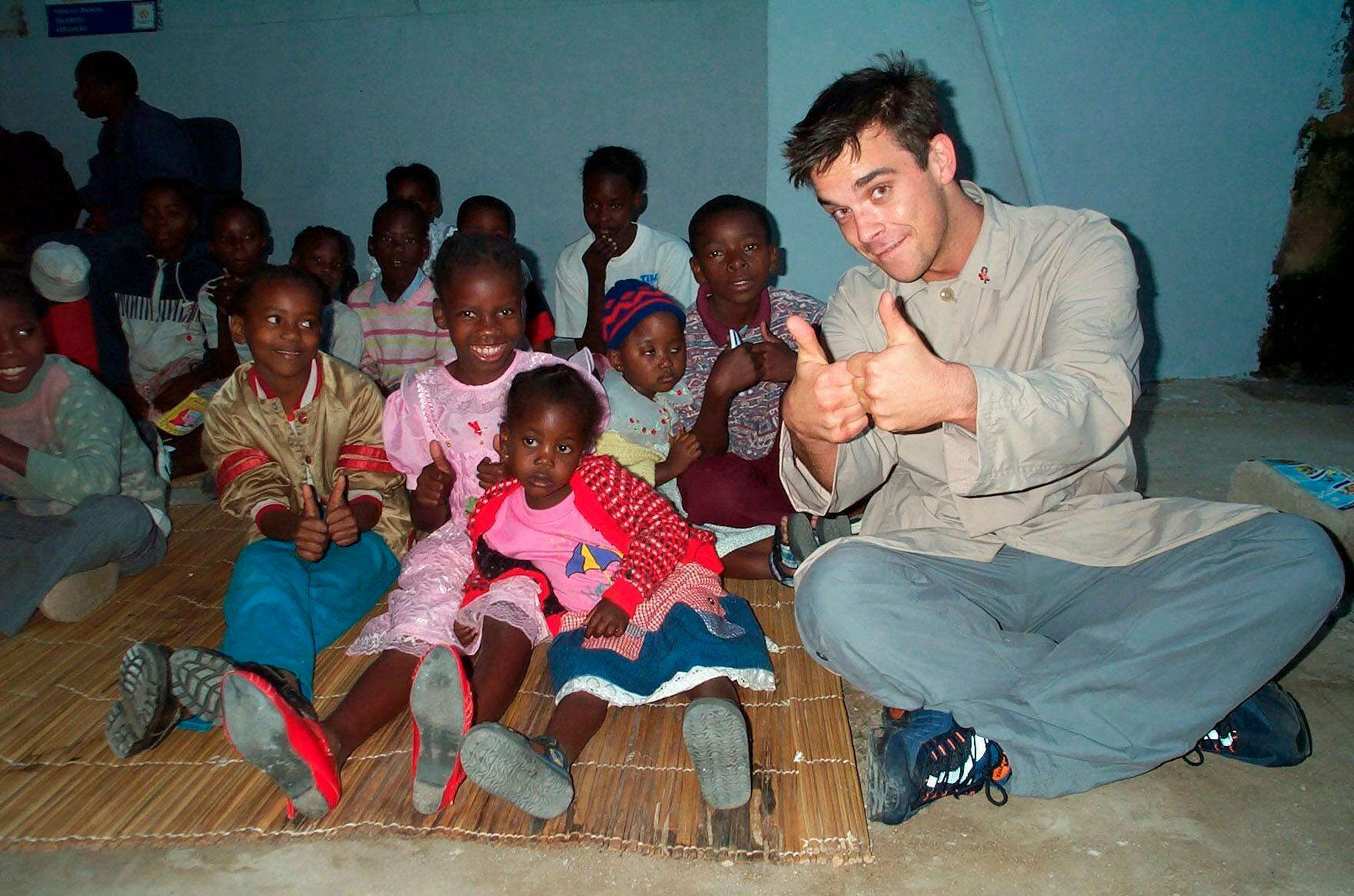Når han ikke synger, går Robbie op i velgørende arbejde i blandt andet Afrika. Her er stjernen på tur for UNICEF i 2000.
