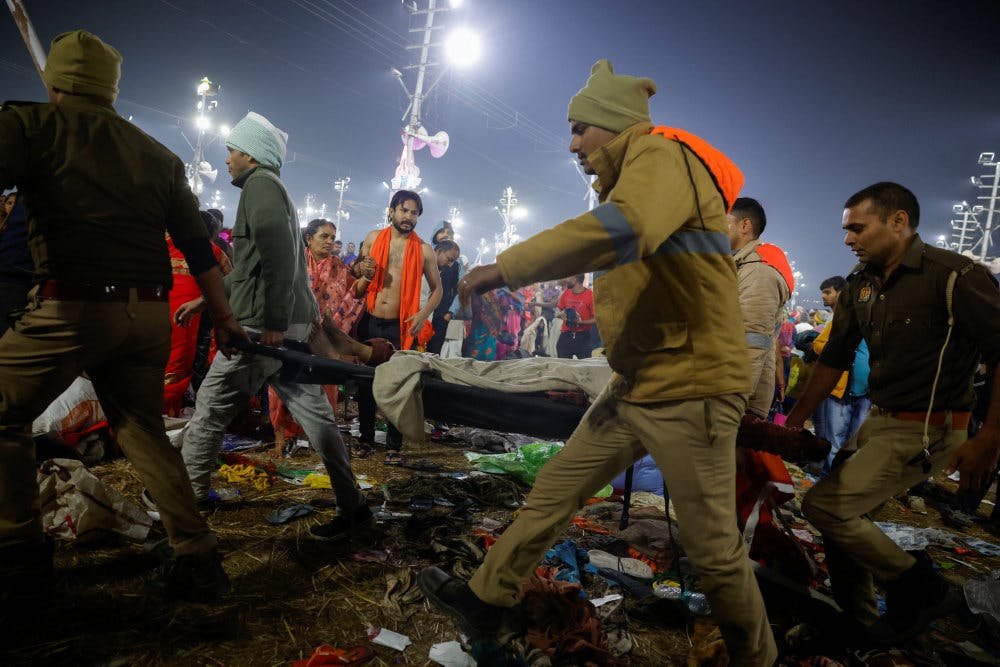 Politibetjente bærer en af de omkomne væk fra festivalpladsen i Prayagraj i Indien. Her har flere pilgrimme onsdag mistet livet, efter at der udbrød panik under en religiøs fejring.