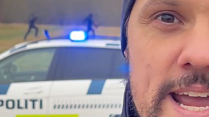 En politibetjent synger i forgrunden, mens en anden politibetjent jagter en "kriminel" i baggrunden.