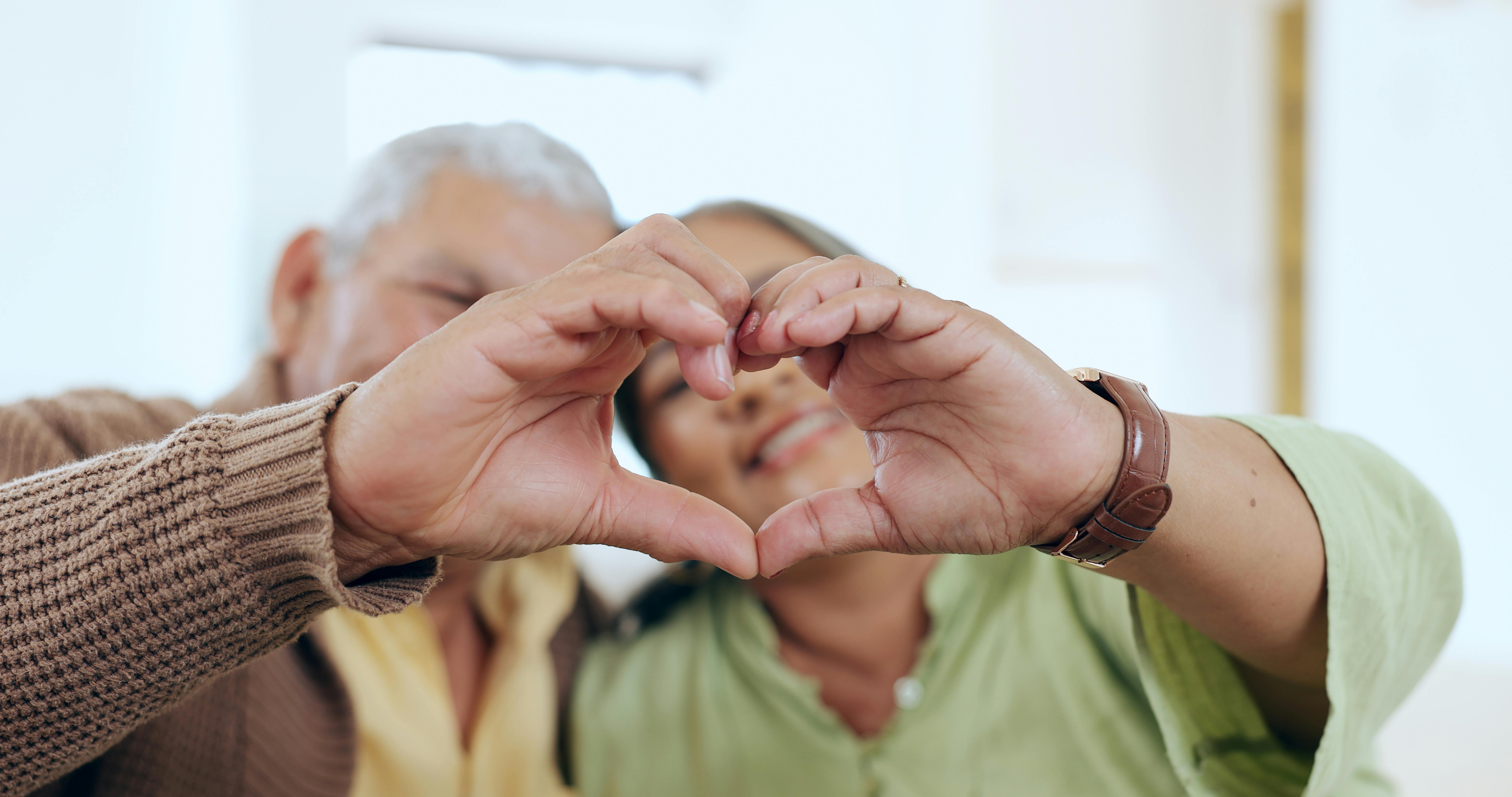 Care, heart hands or old couple with support, love or hope in a marriage commitment at home together. Happy, valentines day blur or romantic senior man with smile or elderly woman on anniversary.