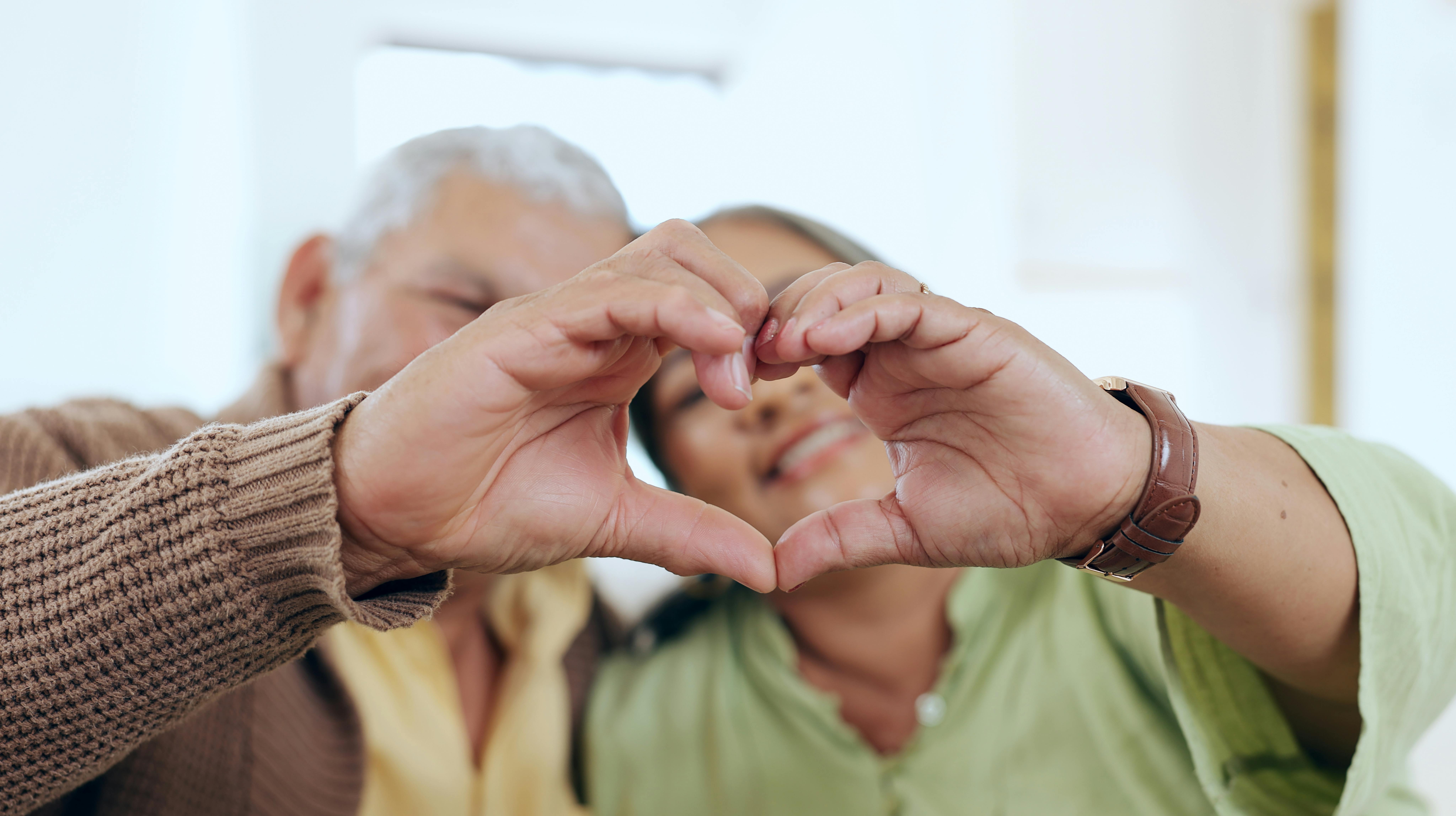 Care, heart hands or old couple with support, love or hope in a marriage commitment at home together. Happy, valentines day blur or romantic senior man with smile or elderly woman on anniversary.