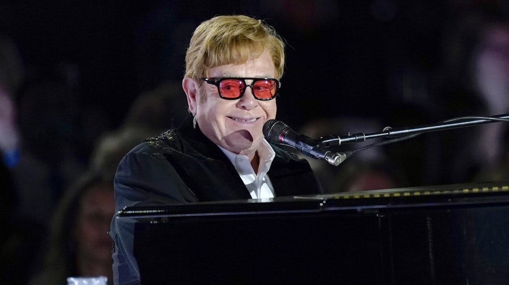 Briten sir Elton John har optrådt med sine mange hits verden over. I 1970 fik han sit første hit på den britiske top-10. Det var "Your Song". Han er nu 77 år. Billedet er fra 2022, da han spillede på plænen ved Det Hvide Hus i Washington D.C. - Foto