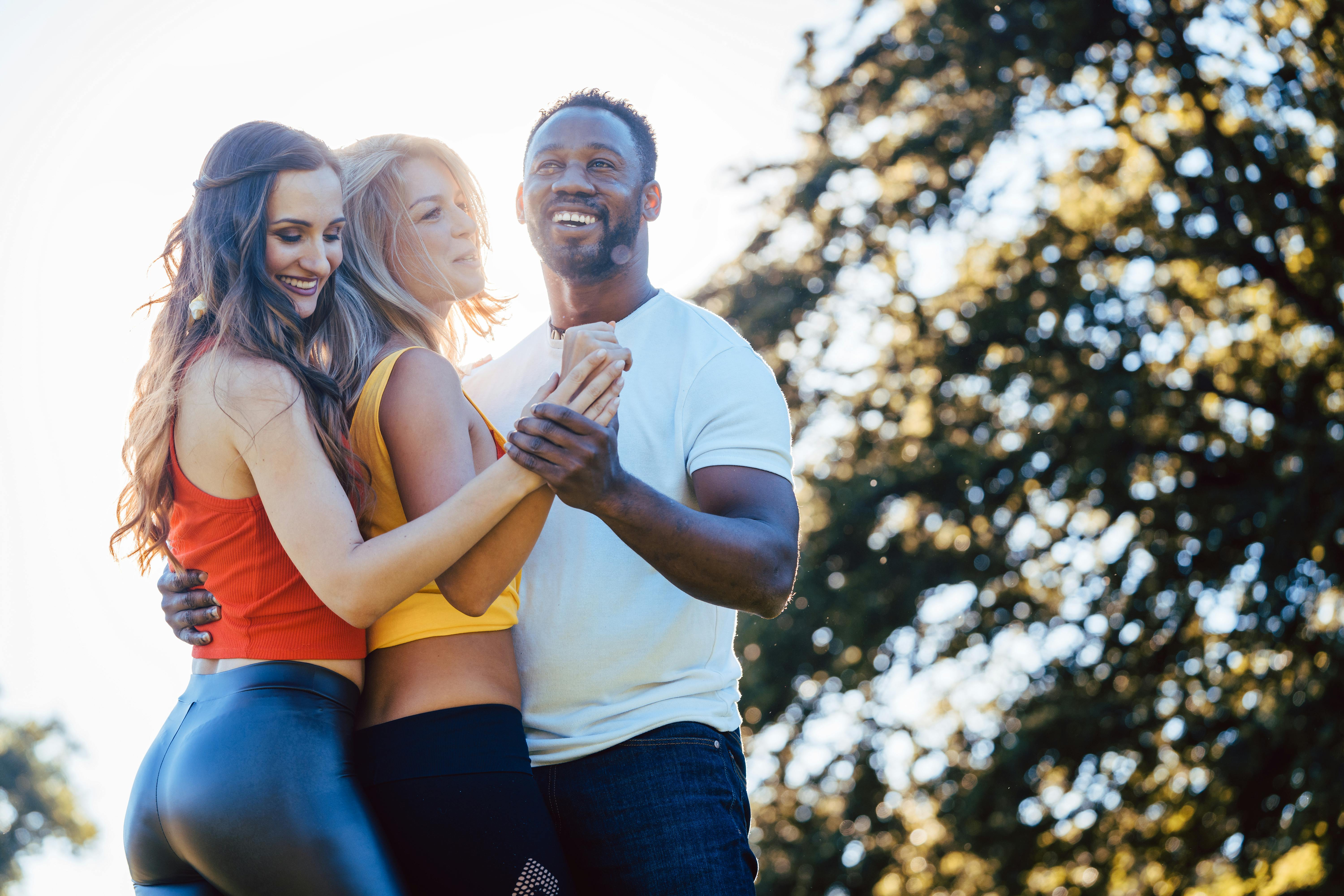 Three friends having fun dancing kizomba on a meadow in afternoon