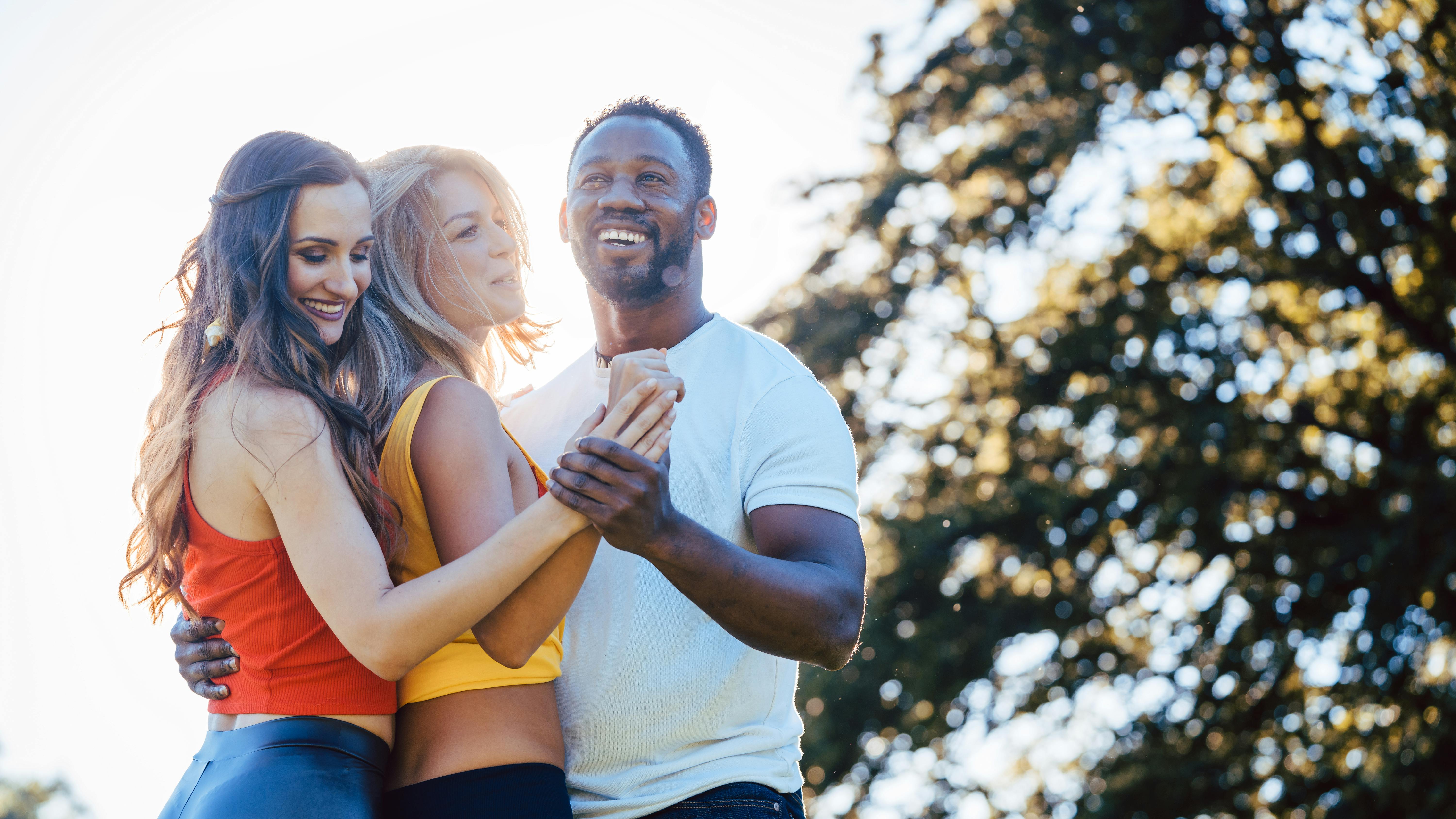 Three friends having fun dancing kizomba on a meadow in afternoon