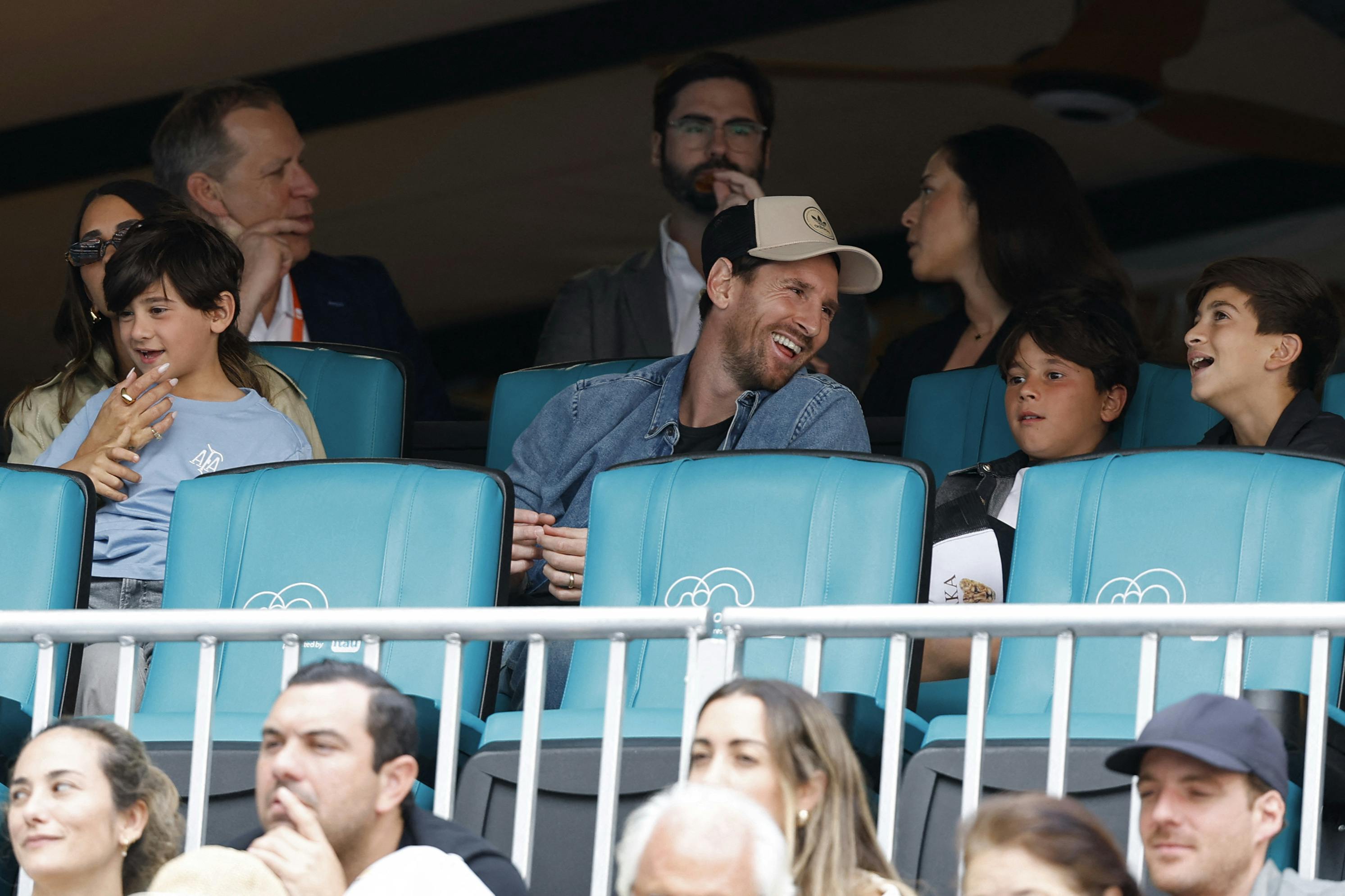 Mar 28, 2025; Miami, FL, USA; Inter Miami forward Lionel Messi (T-M) sits with his family in the stands during the match between Novak Djokovic (SRB) and Grigor Dmitrov (BUL)(both not pictured) in a men's singles semifinal on day eleven of the Miami Open at Hard Rock Stadium. Mandatory Credit: Geoff Burke-Imagn Images
