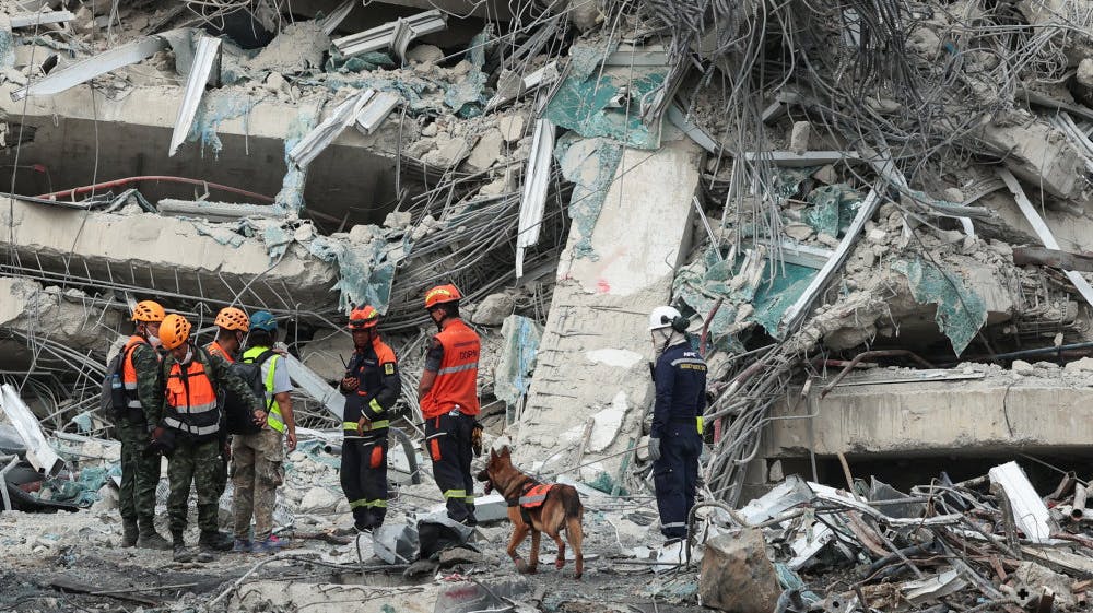 Redningsfolk får søndag morgen assistance fra hunde til at finde frem til døde og levende efter kollaps af højhus, der var i gang med at blive opført, da det fredag kollapsede under jordskælv. 
