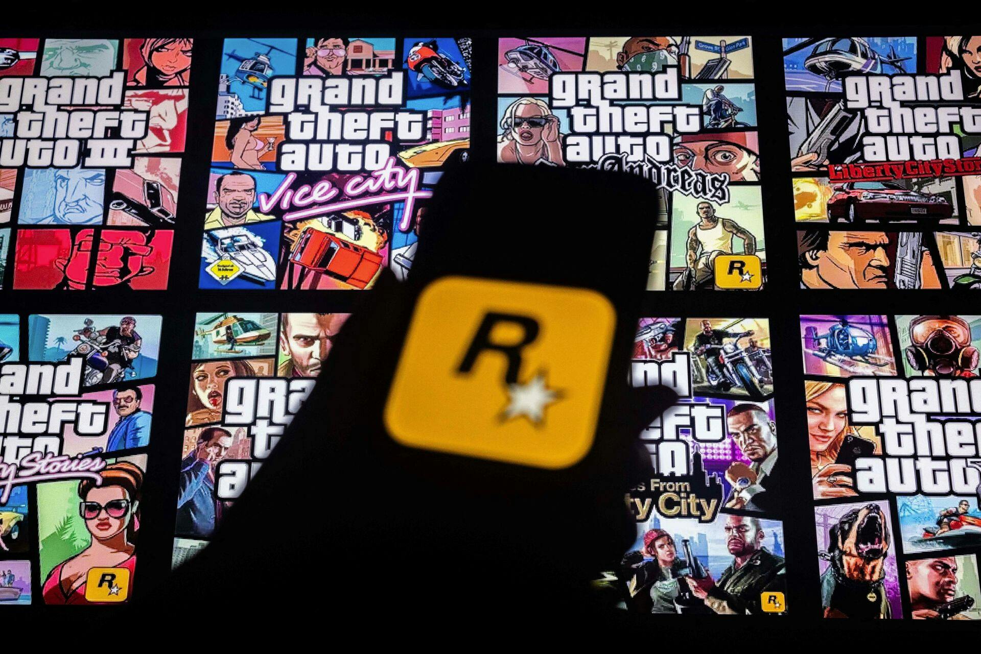(FILES) This illustration shows a logo of Rockstar Games on a smartphone screen and covers of video game series Grand Theft Auto (GTA) on a TV screen in New York on November 27, 2023. The much-awaited release of Grand Theft Auto VI, the latest installment of the popular video game series, has been postponed by several months to May 2026, its publisher said May 2, 2025. (Photo by Yuki IWAMURA / AFP)