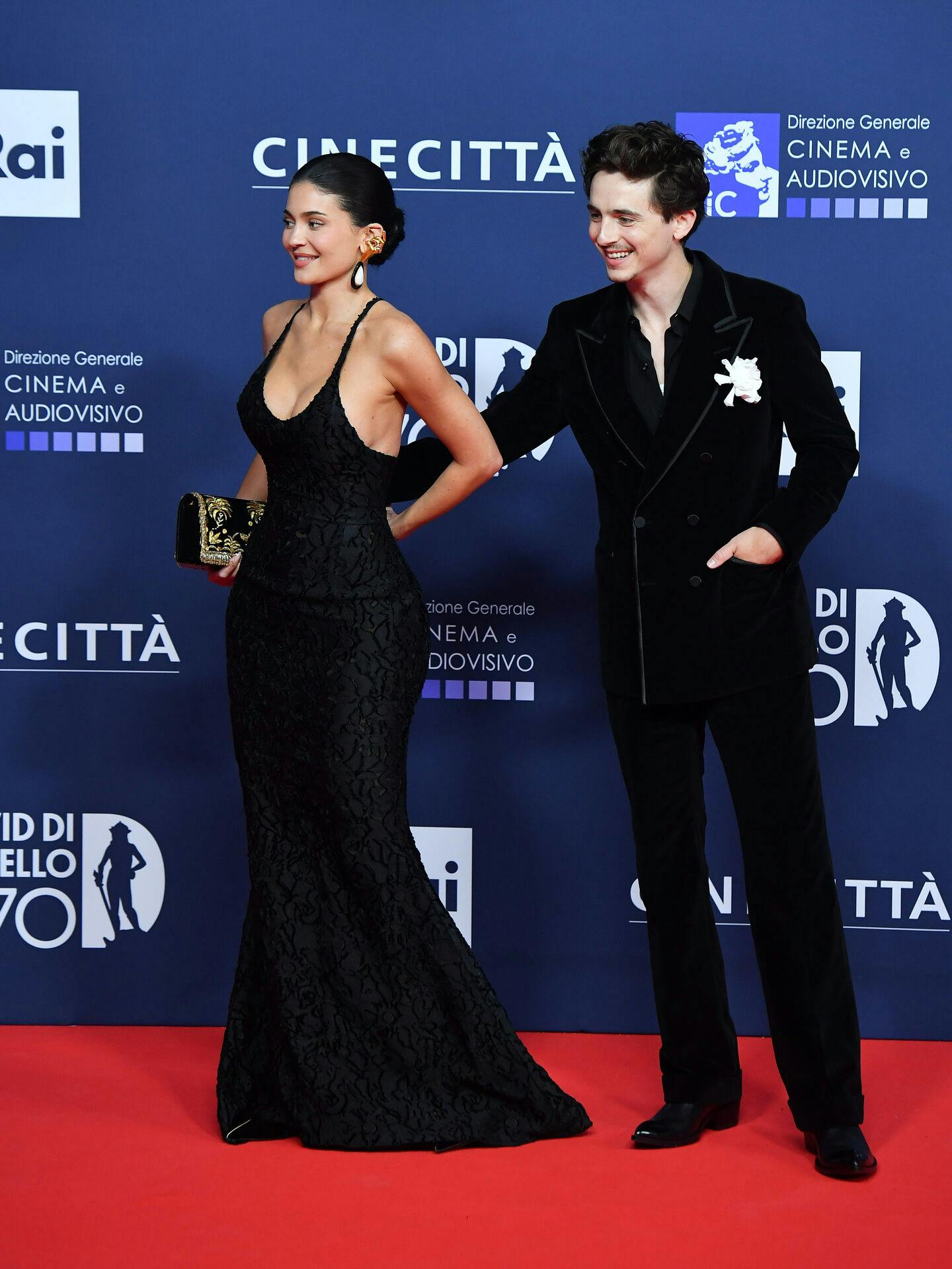 Timothée Chalamet matcher Kylie i sort veloursæt med hvid knaphulsblomst.