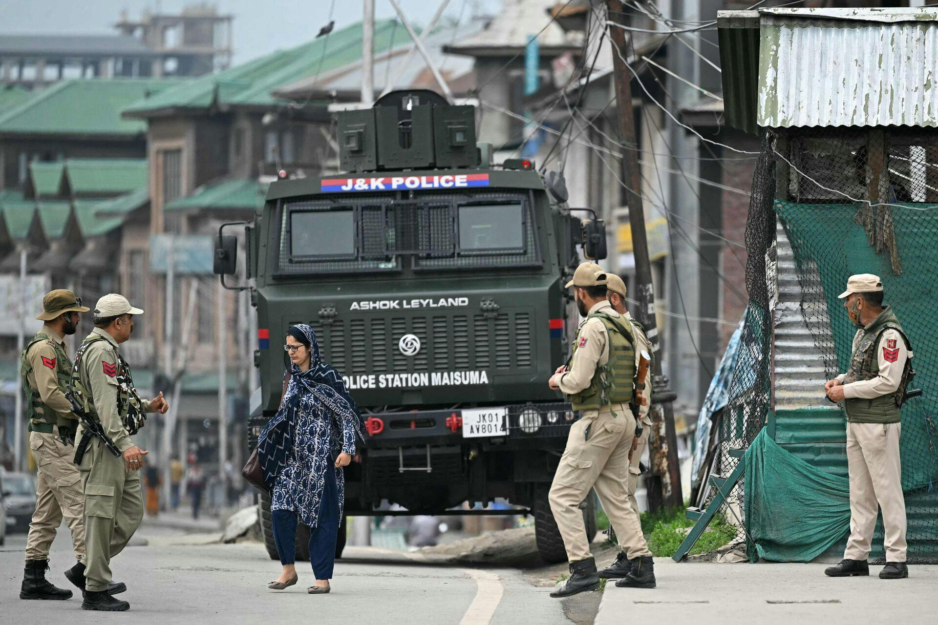 Indian policemen stand guard as a woman walks along a street in Srinagar on May 9, 2025. India and Pakistan accused each other on May 8 of carrying out waves of drone attacks, as deadly confrontations between the nuclear-armed foes drew global calls for calm. (Photo by Sajjad HUSSAIN / AFP)